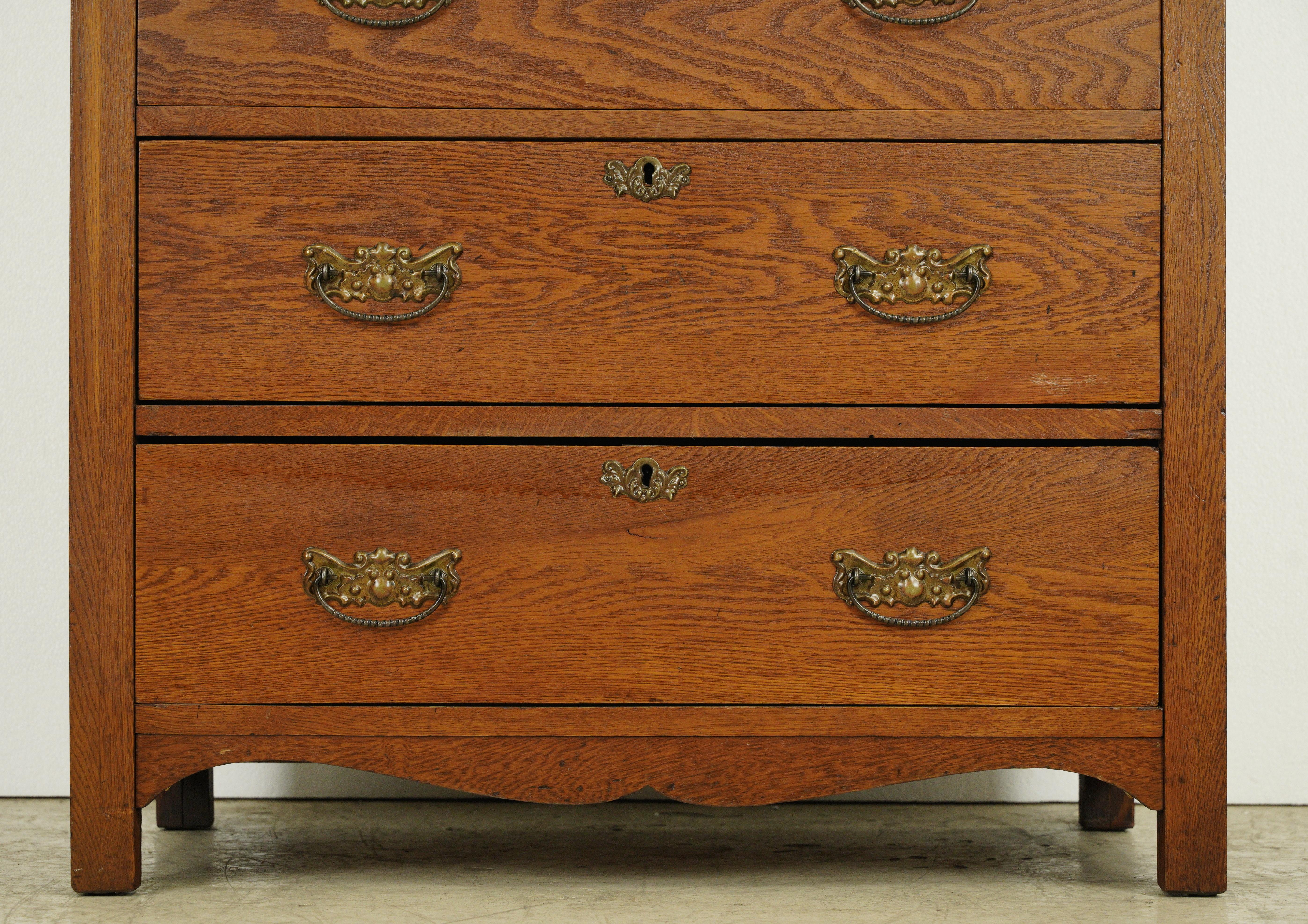 Dark stained oak highboy dresser with five dovetailed drawers and brass and steel hardware. Good condition with appropriate wear from age, with minor dings and scratches. One available. Please note, this item is located in one of our NYC locations.