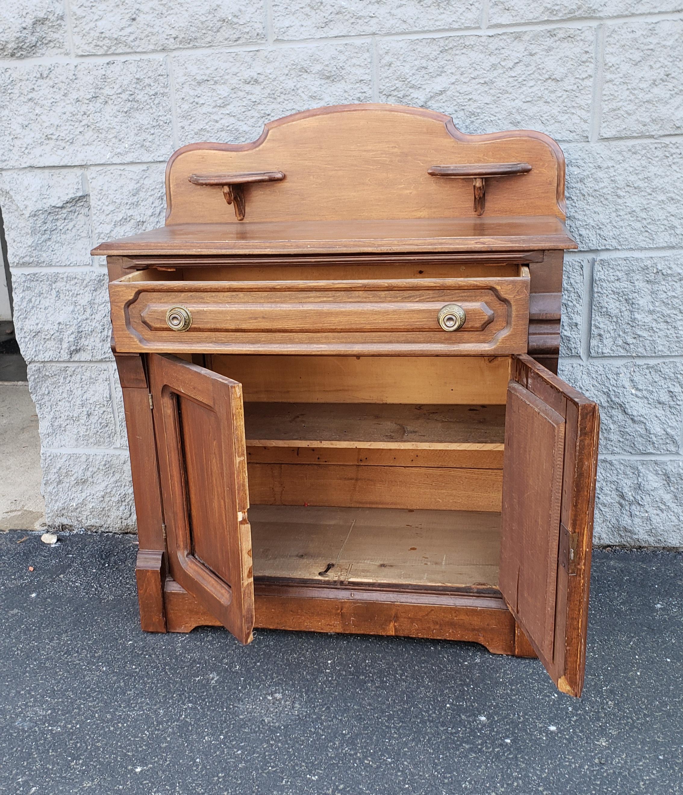 An early 20th century american fruitwood washstand featuring a single large drawer with peg joints,, a lower storage with shelf. Very good antique condition. Floor to counter top is 27.75