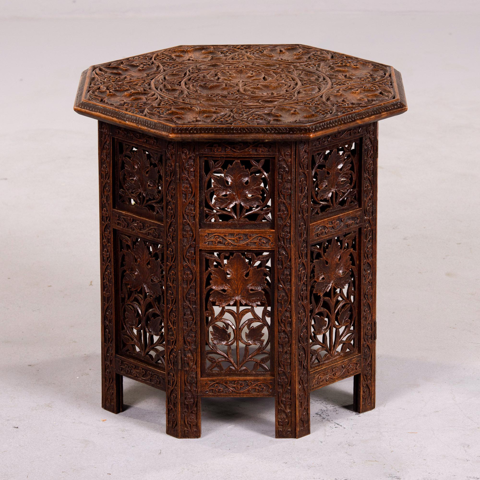  Found in England, this carved folding octagonal table was made in India and dates from the 1920s. The base has eight legs and panels with hinges so that with the top removed, the base can be folded flat. The base is covered with intricate, open