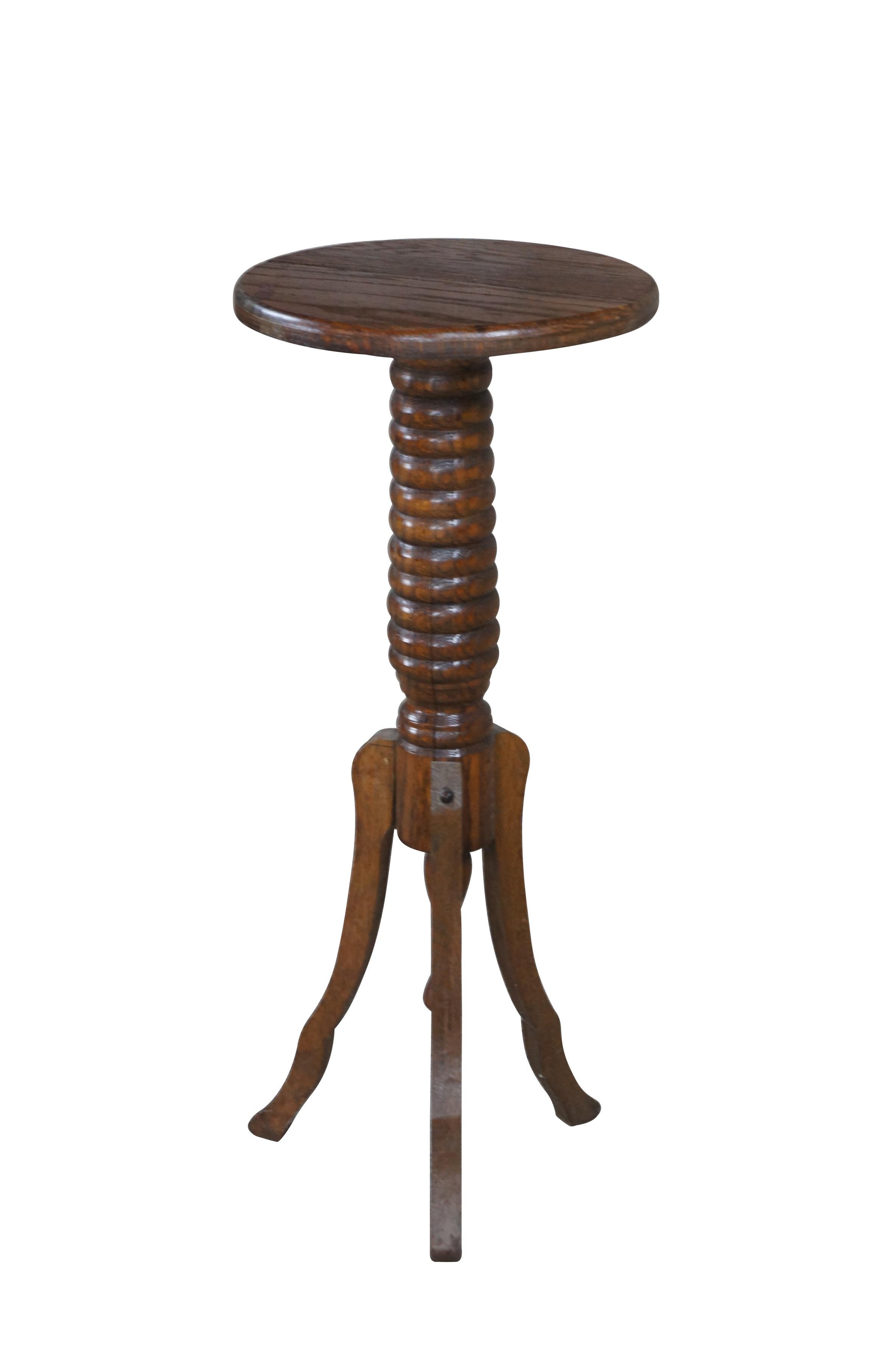 An early 20th century pedestal, plant / sculpture stand.  Made from oak with a round top over a turned and ribbed support leading to a tripod base.  Includes turned down finial.

Dimensions:
12.5