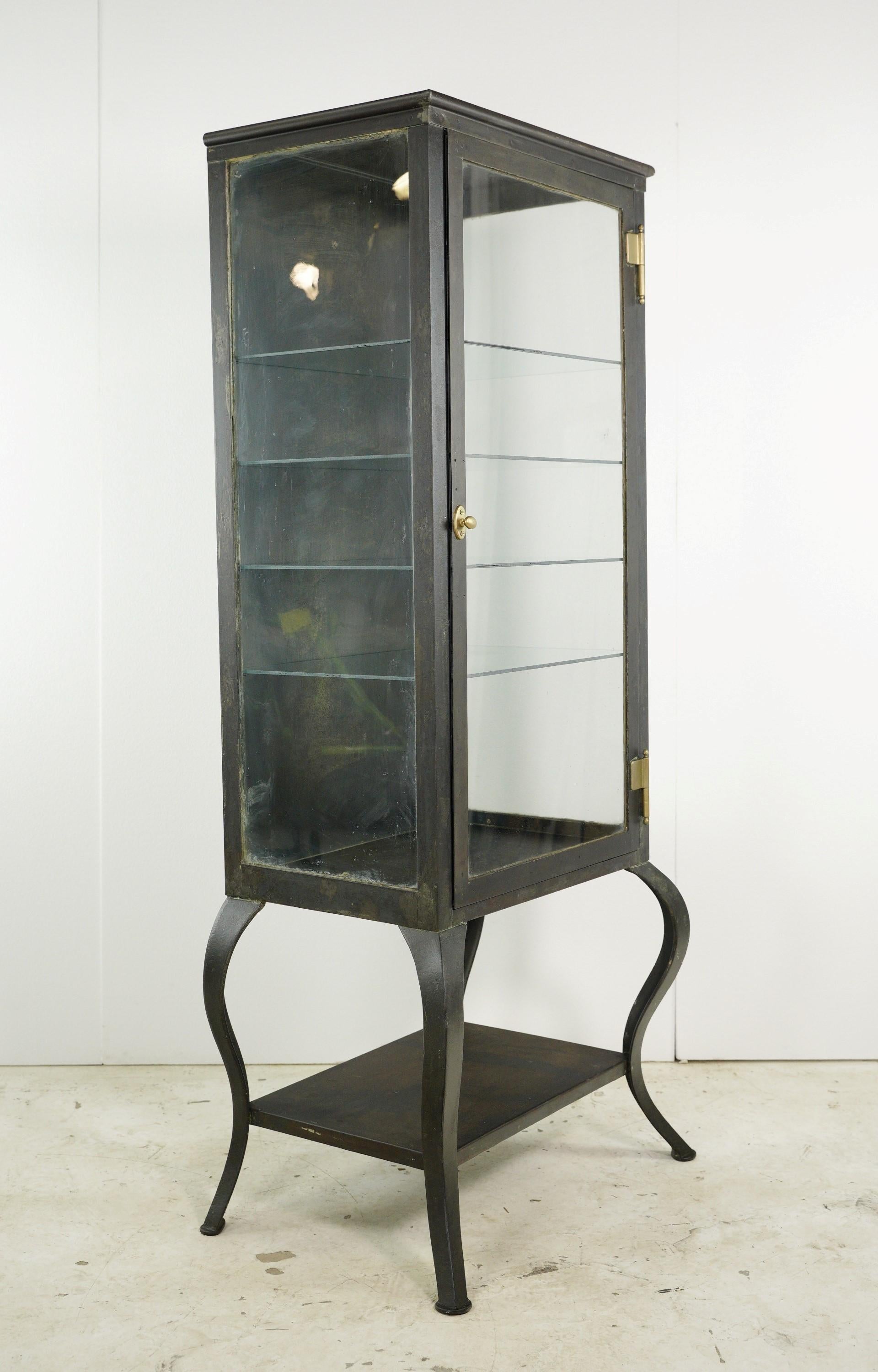This restored antique steel glass shelves medical cabinet is a true gem of the past. With its sturdy steel frame, brass hardware, cabriole legs, and four glass shelves, it showcases antique craftsmanship. This cabinet offers storage and adds a touch