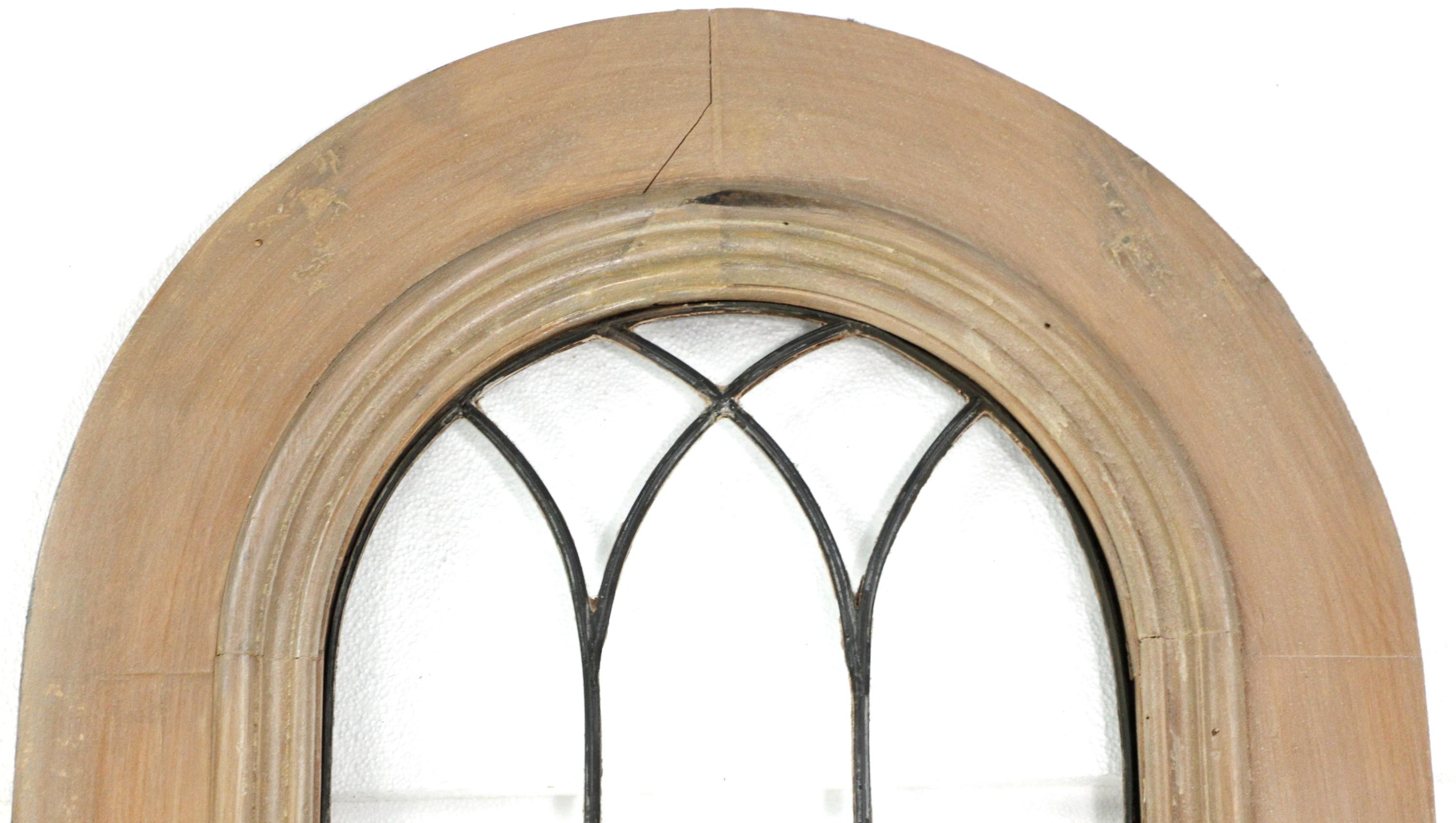 20th century wood door featuring an arched top and done in a light color stain. The window itself has 21 leaded clear glass panes. Bottom of the door features a single wood panel. Some chips and a large crack in the arched top of the wood frame.