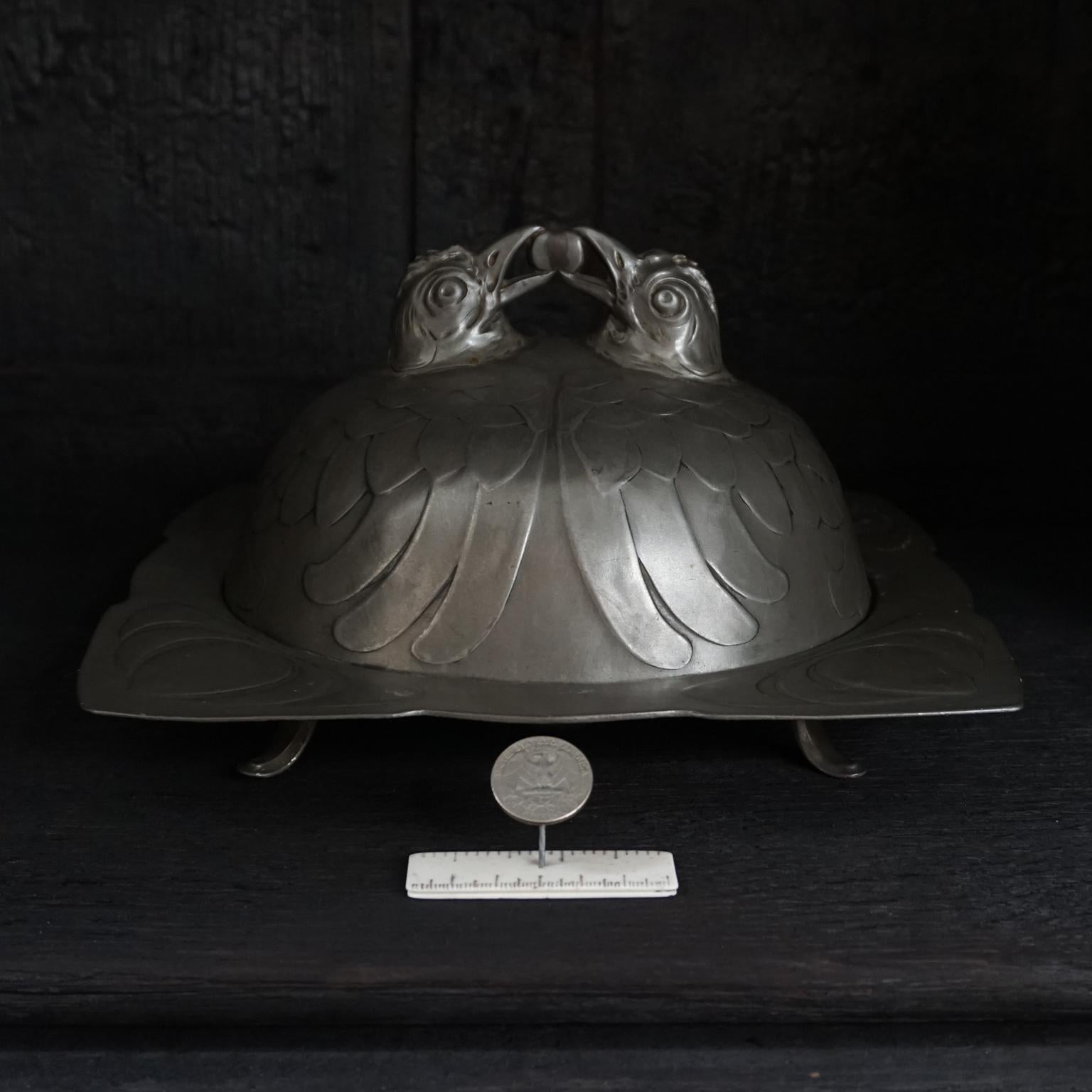 A very rare covered German egg dish manufactured by Walter Scherf & Co. in Nürnberg, under the trade name Osiris, early 20th century.
It is moulded to fit eight little eggs. The cover or cloche features two chickens, covered with styled feathered