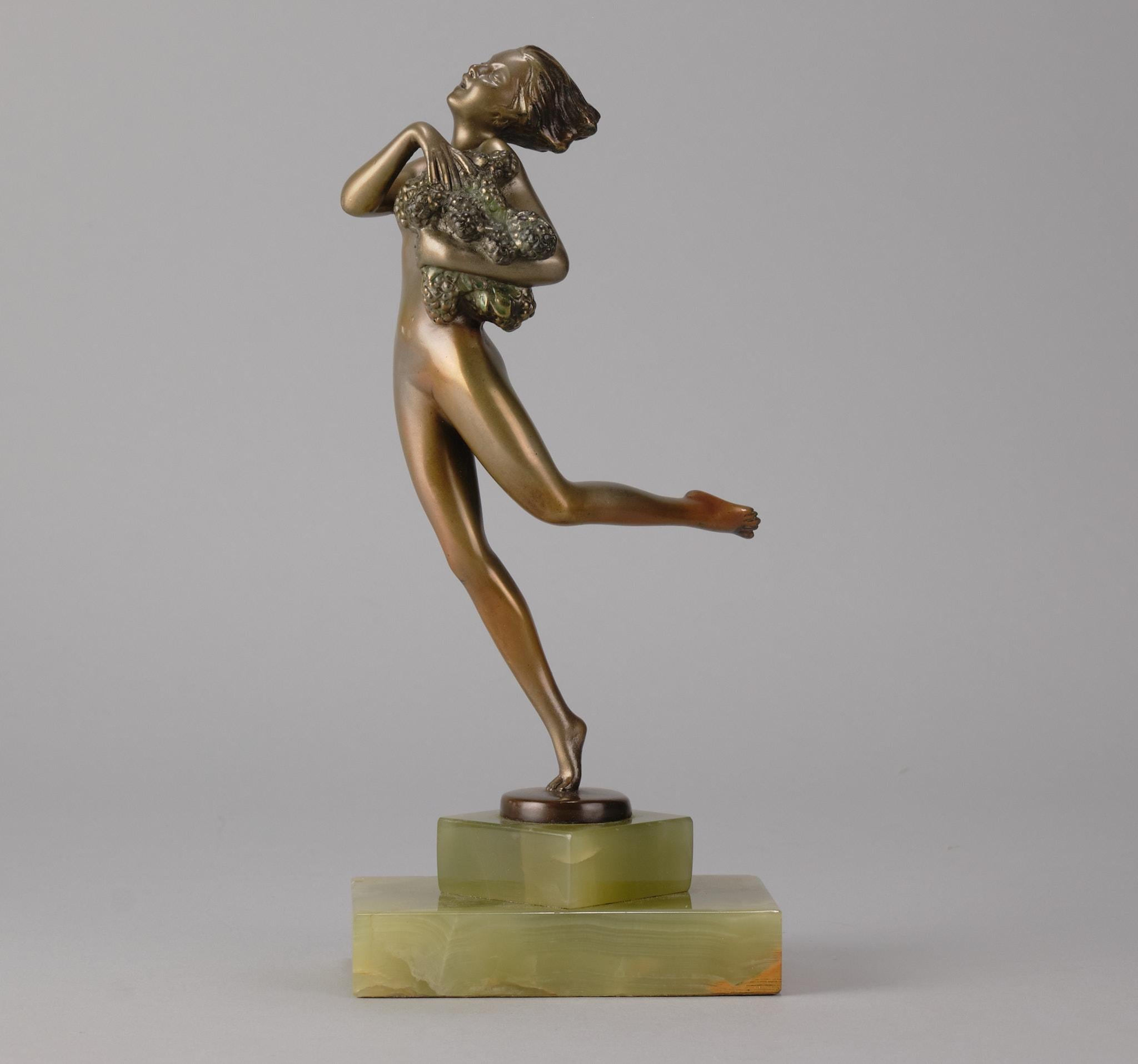 A fabulous early 20th Century cold painted bronze figure of a female Art Deco beauty in a running pose holding a large harvest of grapes under her arm, with fine colour and excellent hand finished detail, raised on a shaped Brazilian onyx base and