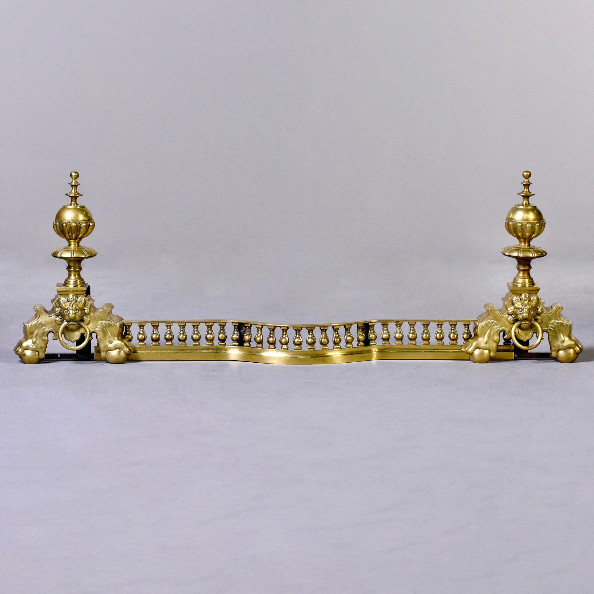 Solid brass adjustable fireplace fender with lion heads, ball and claw feet and tall finials, circa 1930s. Width of fender can be adjusted from 42-52” by sliding lion ends inward or outward. Unknown maker. Found in US.