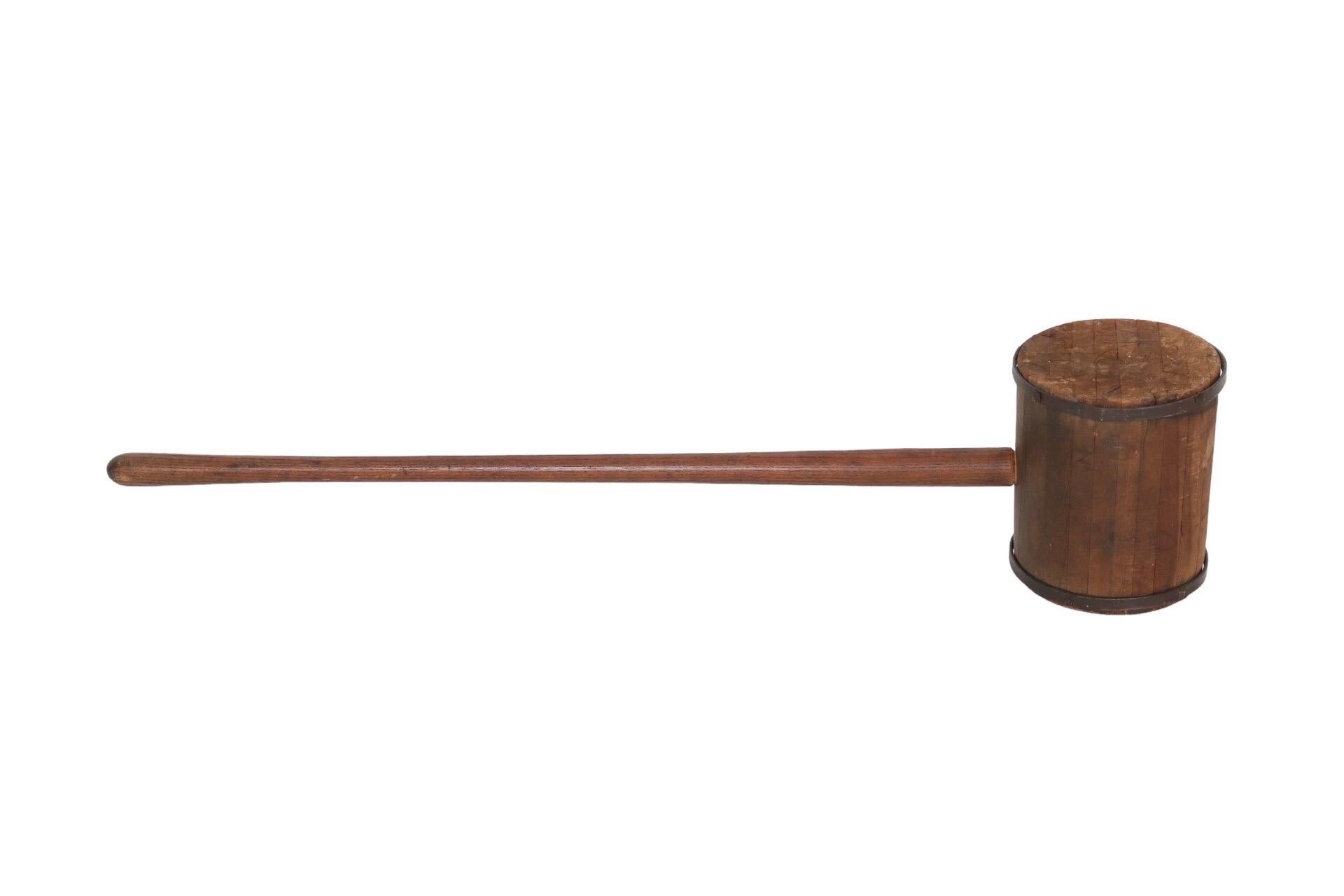 An early 20th century carnival or circus strongman mallet. Made of wood with iron banding around the mallet head. A long handle is ergonomically carved to be comfortable when held.
 