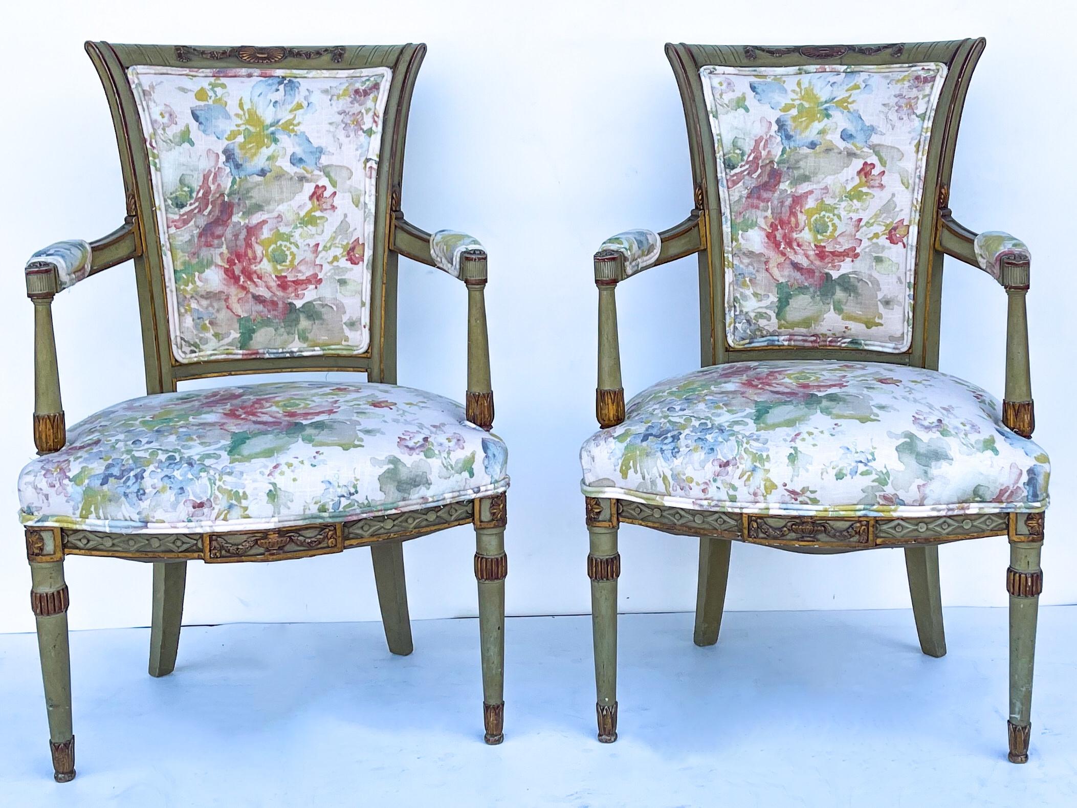 This is a pair of early 20th century carved French bergère chairs. The frames are sage green paint with almost deep russet painted details. The floral linen upholstery is recently done. They are in very good antique condition.