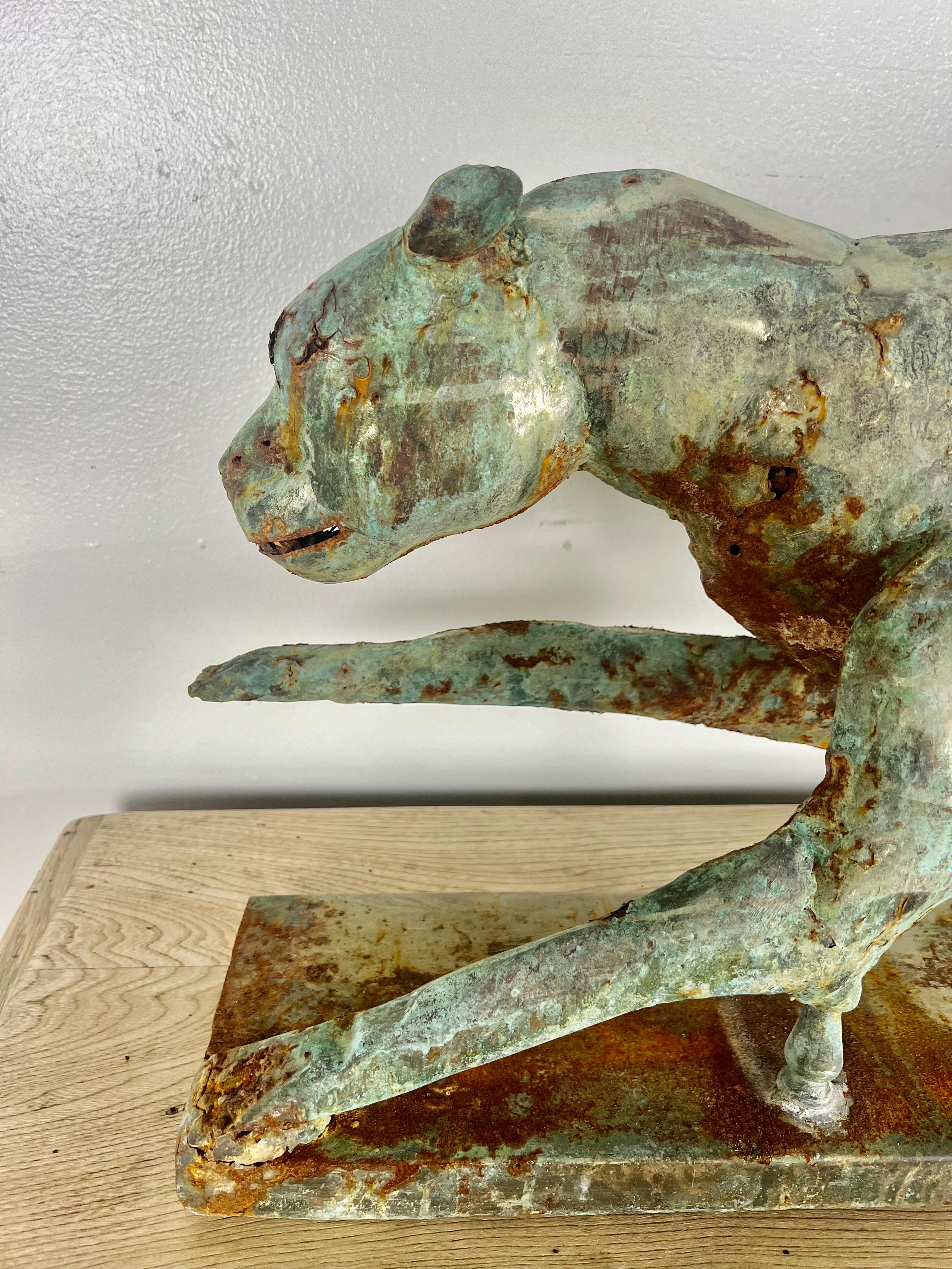 Unusual sculpture of a cheetah mounted on a metal base.  The cheetah is made of metal and has a copper like finish.  The wear can be seen in my photos, but it has a beautiful patina.  The cheetah is weathered and has some areas of rust.