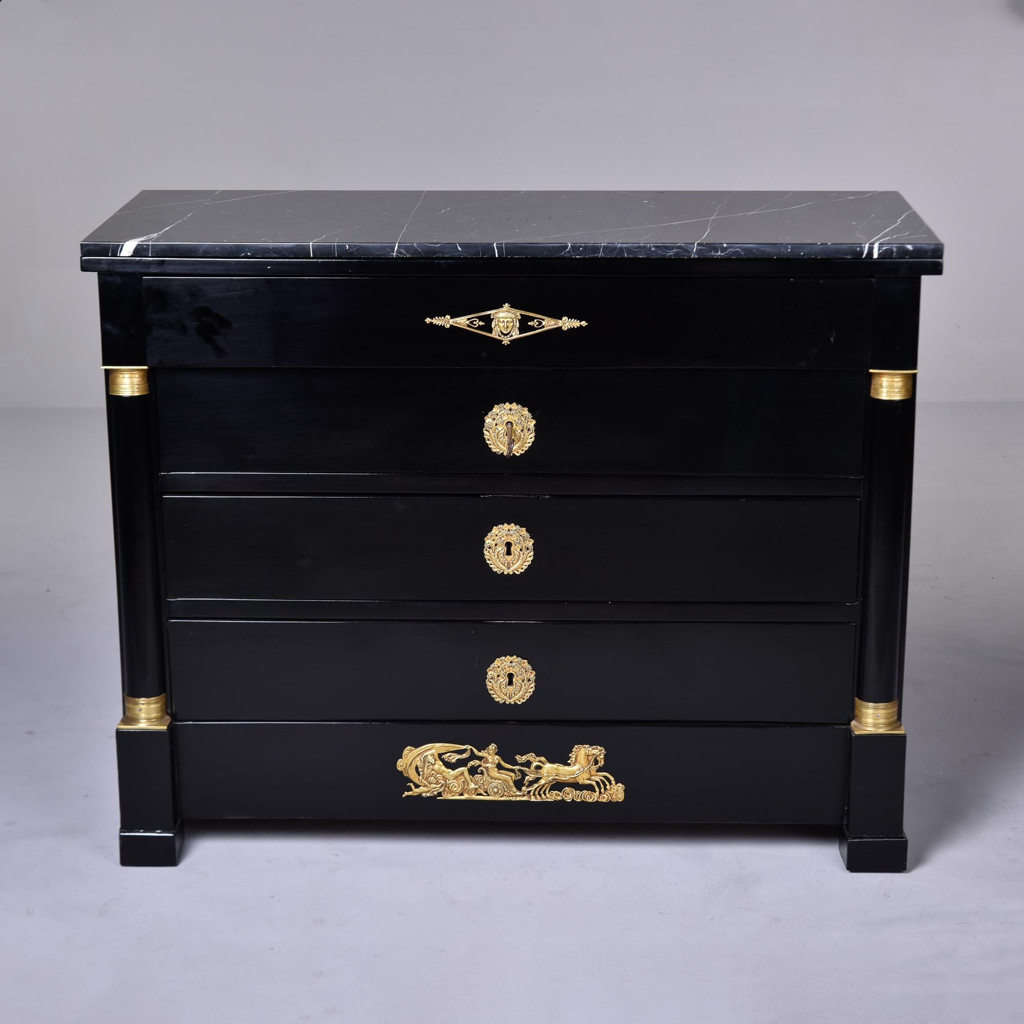 Found in France, this circa 1910 Empire style mahogany chest of four drawers has a new ebonised finish and black marble top. Decorative columns on the front sides have brass trim and all drawers have dovetail construction, and functional locks with