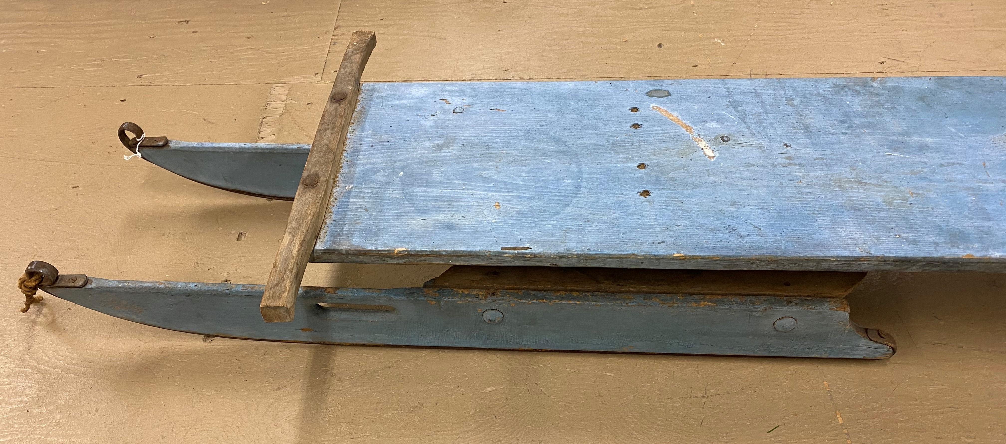 A fine example of an early 20th century wooden traverse with two sets of metal edge runners, in old blue paint. Many of these traverse sleds were used in the logging industry with horses to drag log loads from the woods, and some were used for