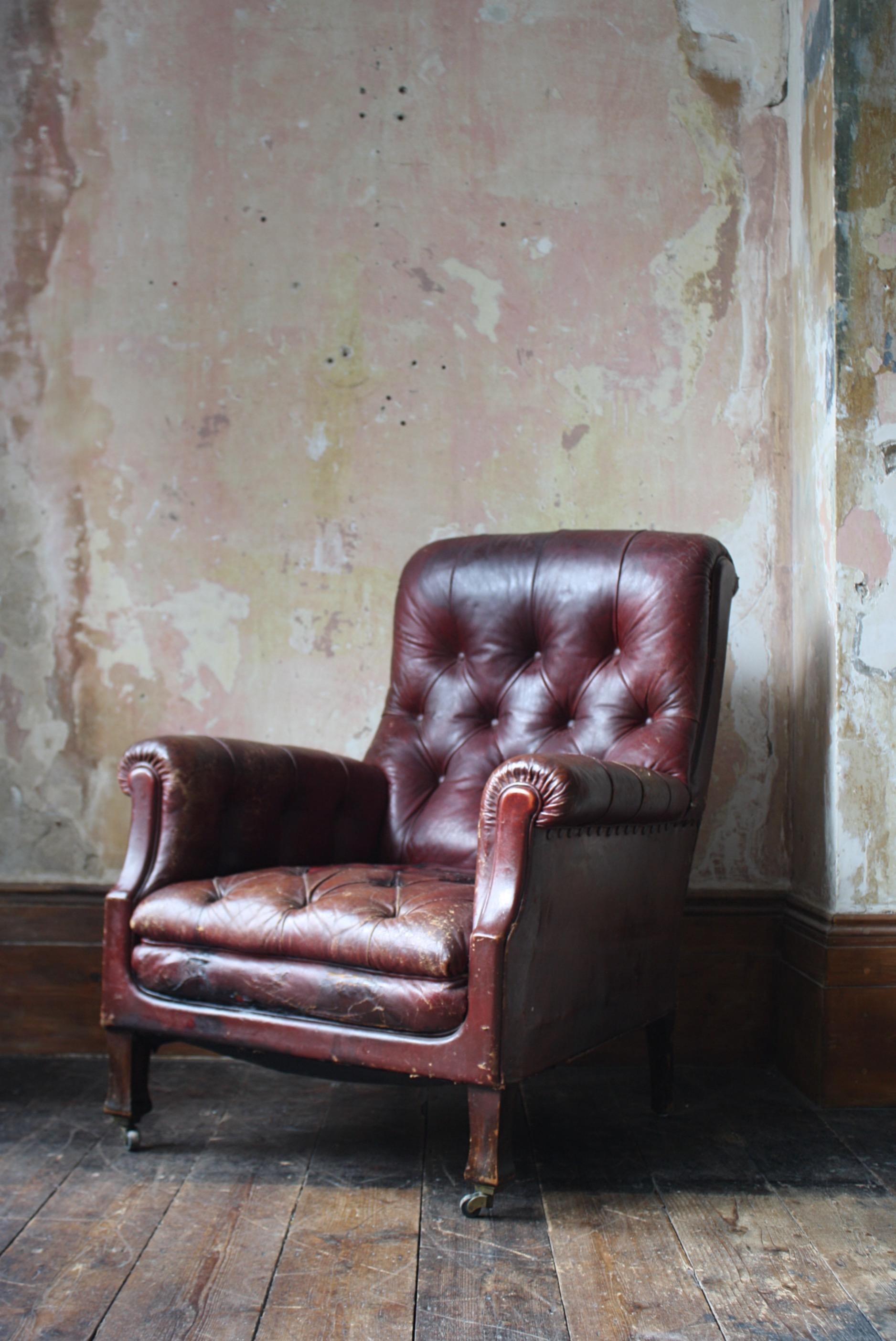 A beautifully worn red button leather deep seated easy armchair, on oak splayed front legs with brass castors.

In all round good condition with typical wear marks and abrasions to the leather, a handful of repairs the two largest examples are found