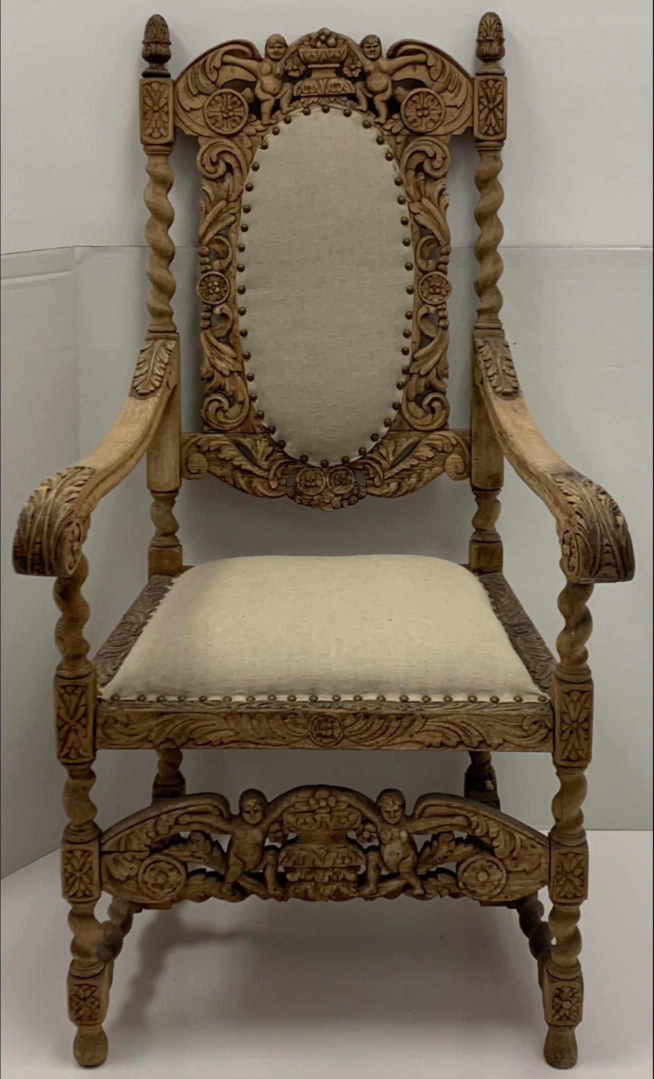 This is an early 20th century English Jacobean style stripped and bleached carved oak throne style arm chair. The linen is a recent addition. It is in very good condition.