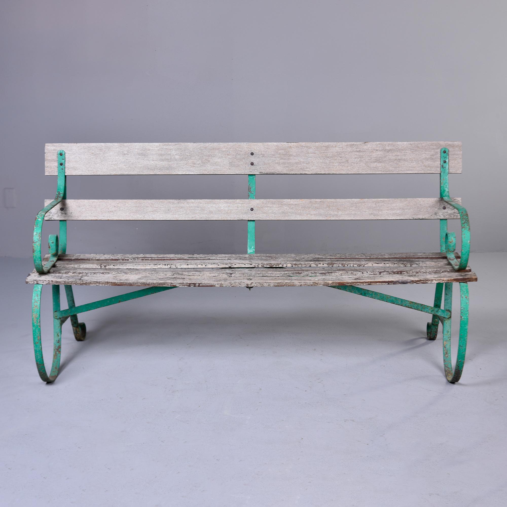 Found in England, this circa 1910 bench has a green metal frame and slat wood seat and back rest. Great curves and patina to painted finish on metal frame. Wood and metal show wear Unknown maker. 

Arm Height:  28.5”     Seat Height:  18.75”
Seat