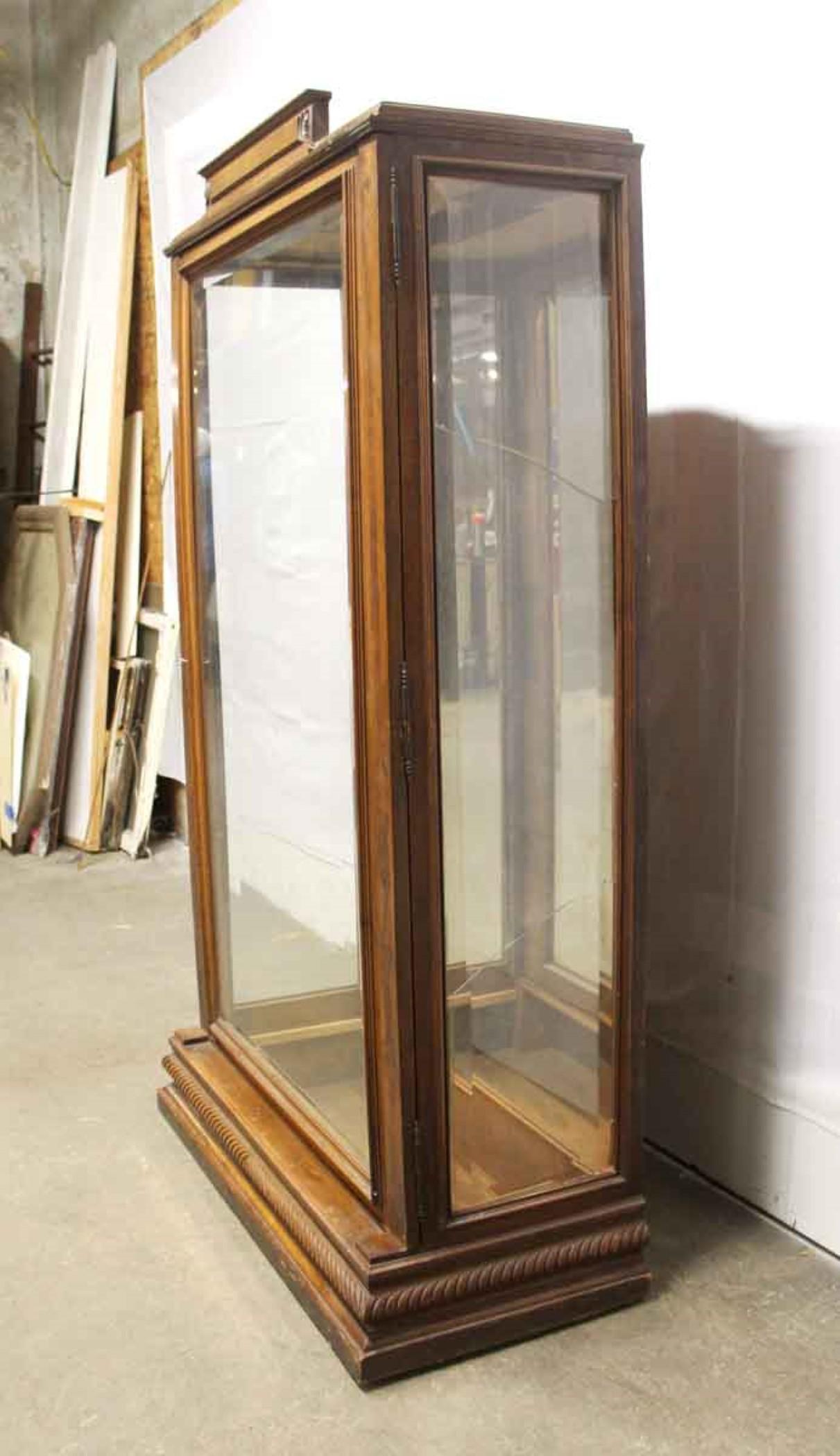 Early 20th century dark stained wood showcase featuring a beveled glass front door, beveled glass sides and a mirrored back. New glass shelves included. Also comes with key for the front door lock. Please note, this item is located in one of our NYC