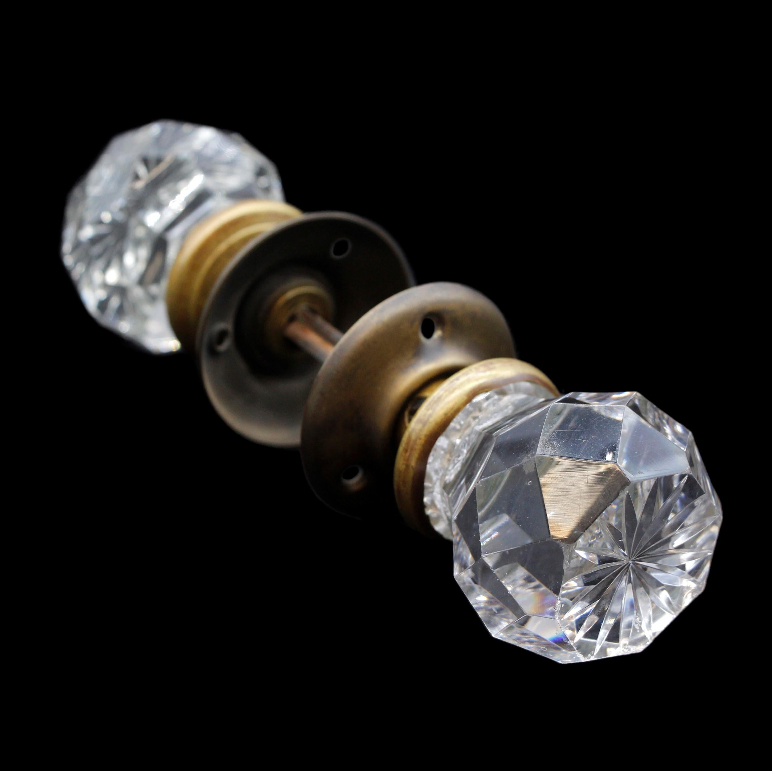 Exquisite early 20th Century faceted cut glass doorknob set. Features an etched star design in the center surface. Comes complete with two brass rosettes and spindle. Priced as one set. This can be seen at our 400 Gilligan St location in Scranton,