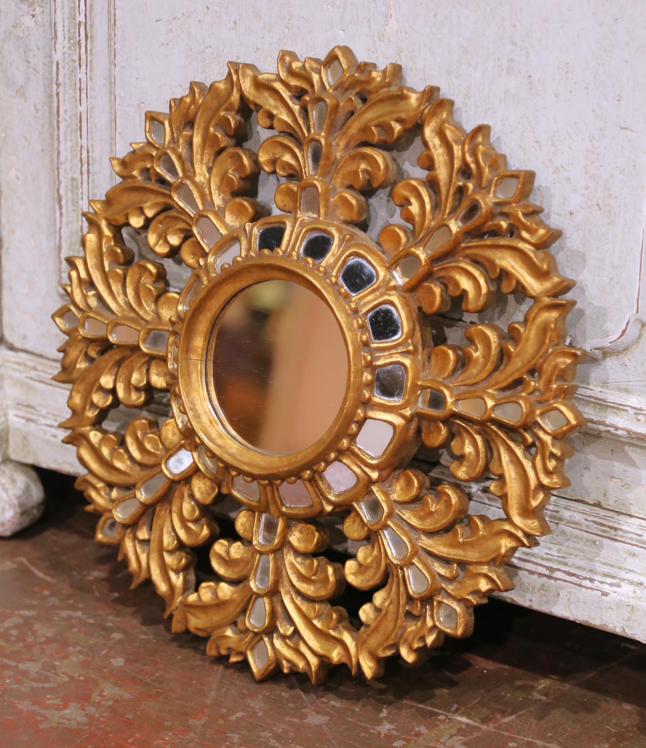 Fabricado en Francia hacia 1920, este llamativo espejo de madera dorada presenta un marco foliado profundamente tallado que irradia alrededor de una placa de espejo circular central. Las hojas de acanto, audazmente esculpidas, están incrustadas con