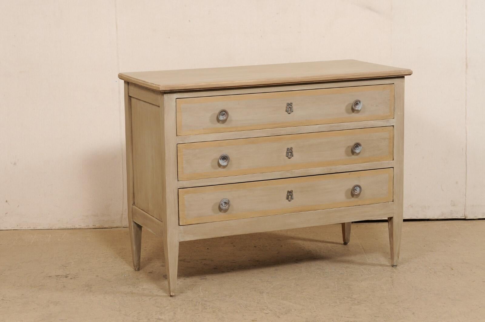 A French Neoclassical style painted wood commode from the early 20th century. This antique chest from France has been designed in clean/linear lines, with a rectangular-shaped top which slightly overhangs the case below which houses three full sized