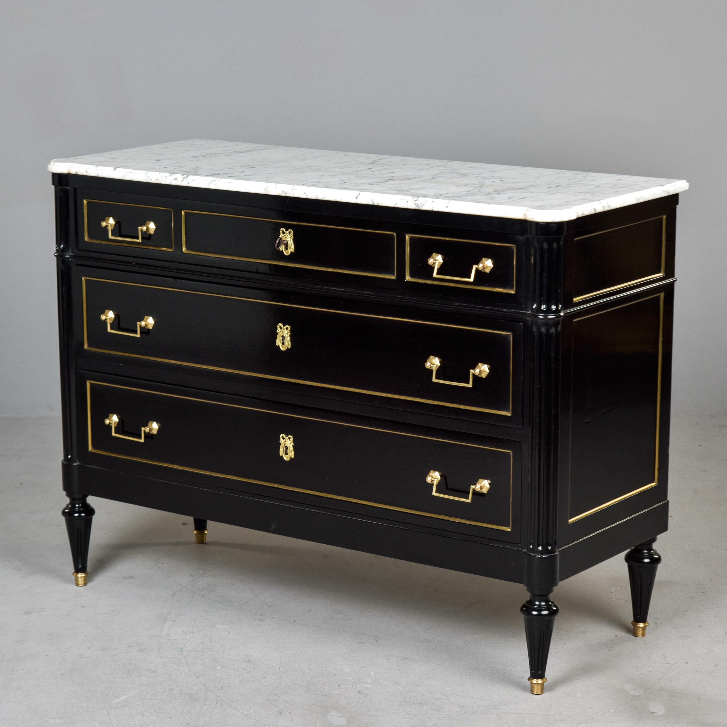 Found in France, this marble-topped commode dates from approximately 1910. Chest of drawers has an ebonised finish, dove tail construction. Side panels and drawer fronts trimmed in brass, turned legs have brass-capped feet. No key found with chest.
