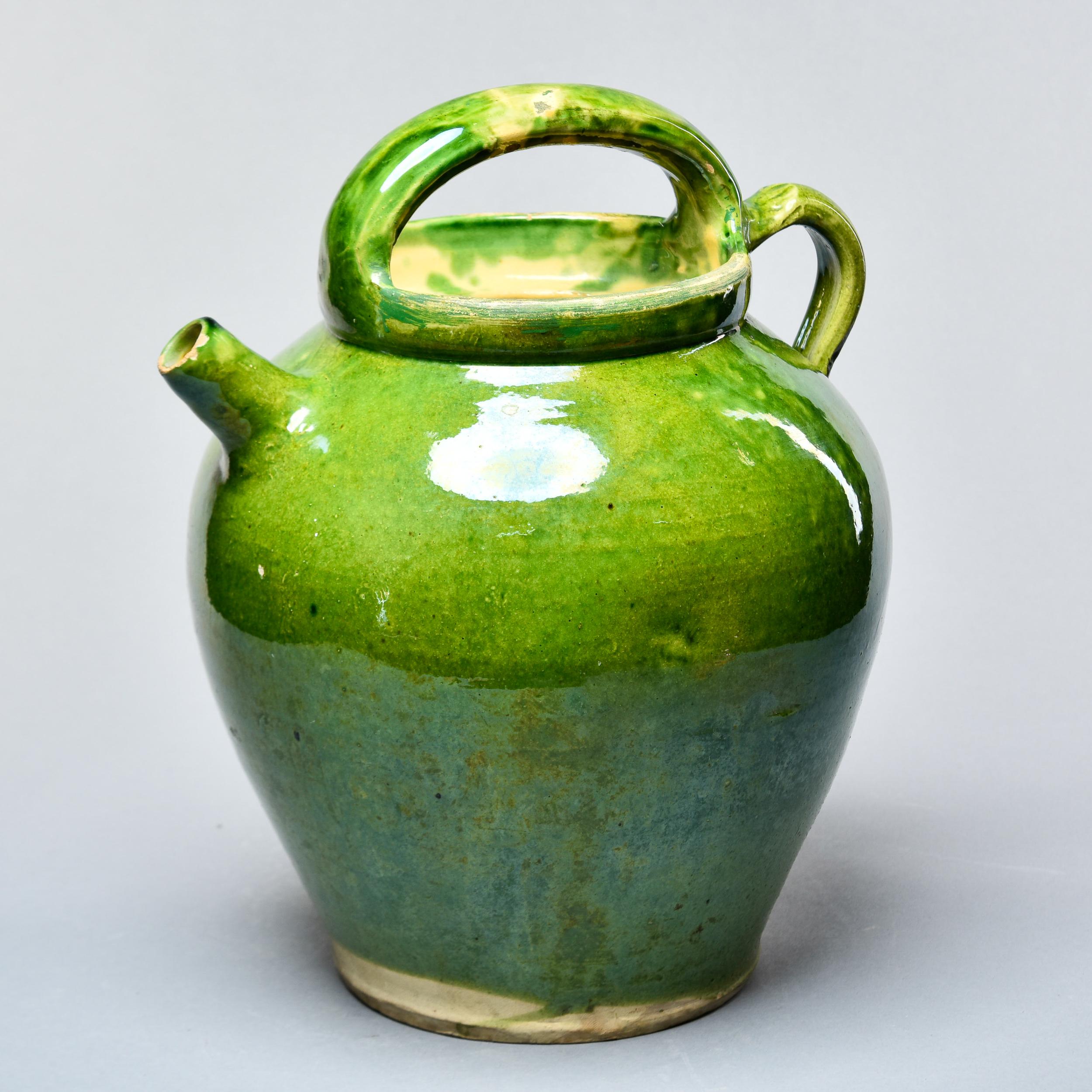 Found in France, this circa 1910 traditional rustic French pot has two handles - one at the side and one on top - a small spout and a jade green glaze. Some scattered wear with flakes to glaze but no repairs or structural issues. Unknown maker.