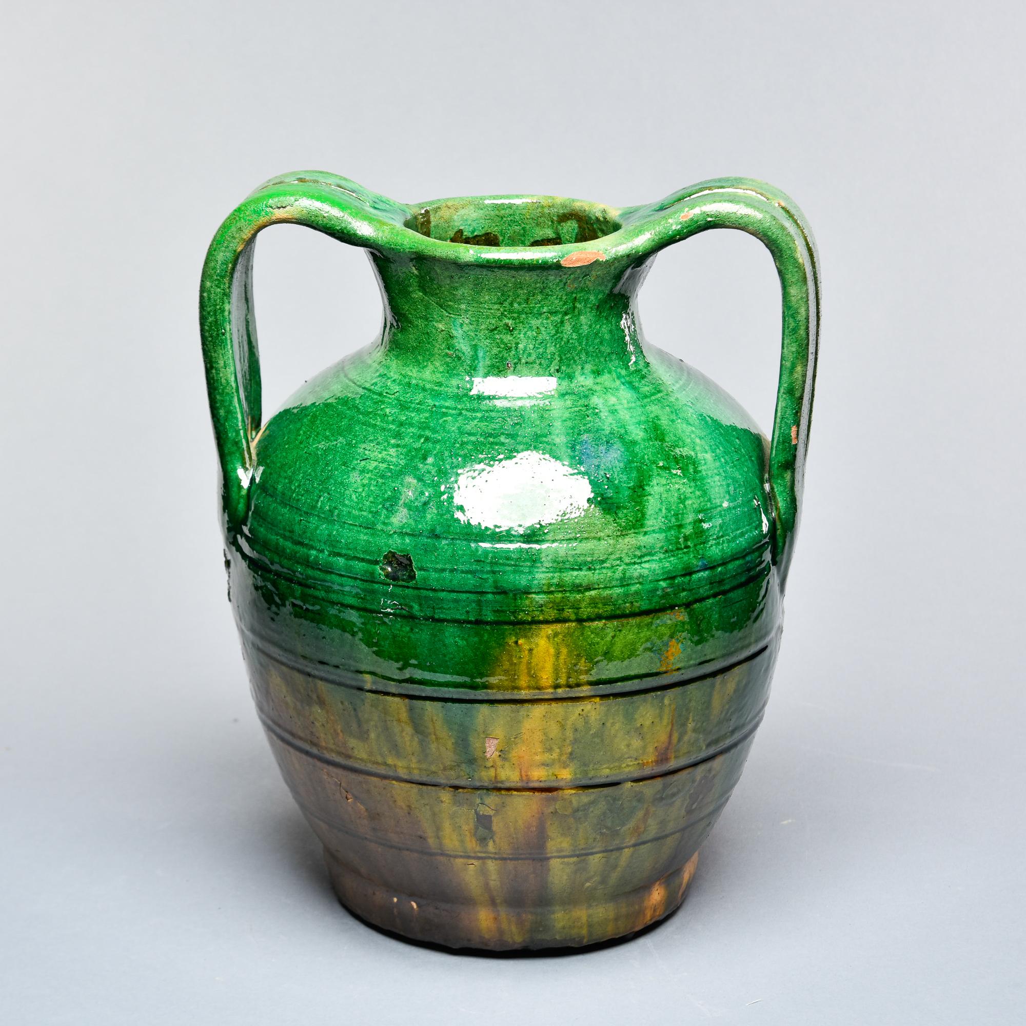 Found in France, this circa 1910 traditional rustic French pot has two curved handles and a jade green glaze with mustard gold under glaze. Some scattered wear with flakes to glaze but no repairs or structural issues. Unknown maker. Several