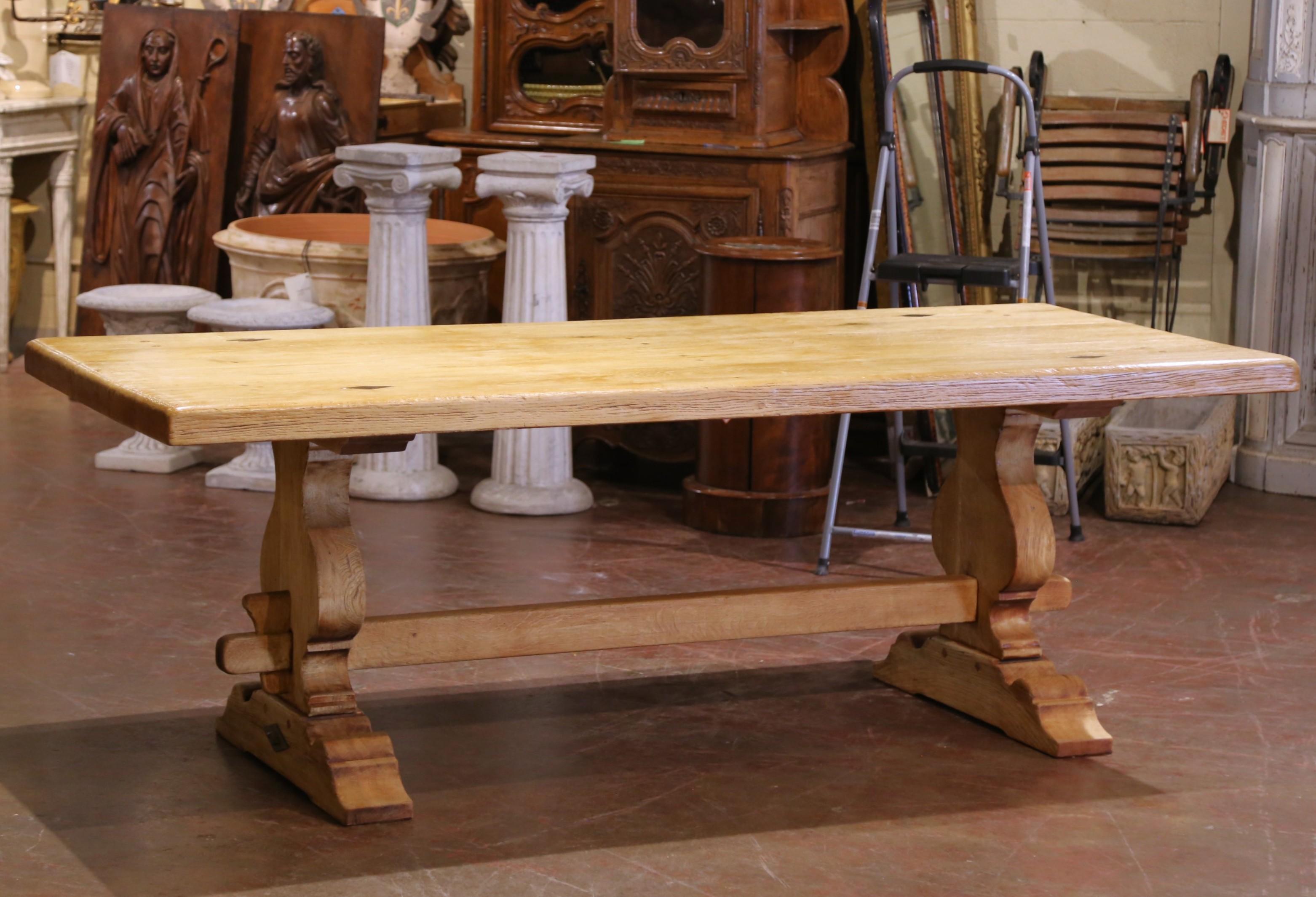 Bring rustic elegance to your dining space with this early 20th-century French refectory table, crafted circa 1920 in the Louis XIII style. Constructed from solid oak and bleached to a light, natural finish, the table features a thick rectangular