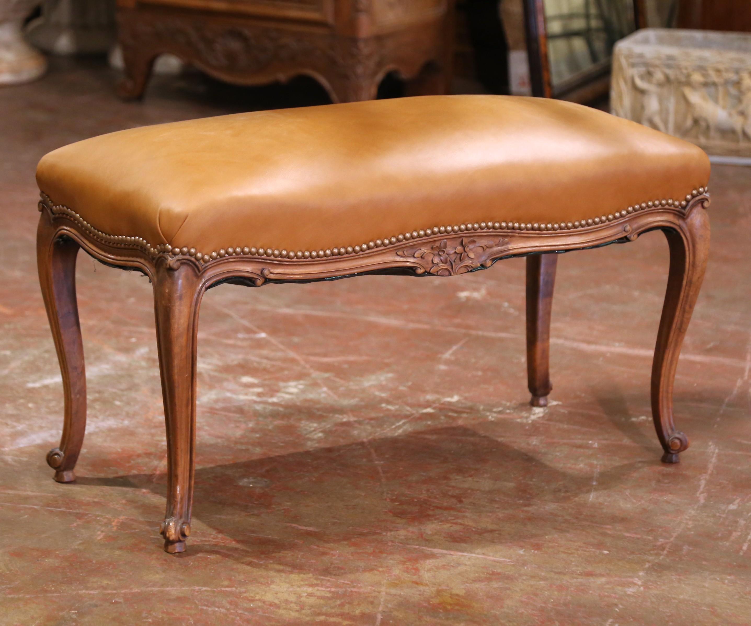 Diese raffinierte französische Bank wurde um 1920 in der Provence gefertigt und verkörpert die anmutige Eleganz des Stils Louis XV. Der aus massivem Nussbaumholz gefertigte Rahmen hat eine sanft geschwungene Silhouette mit geschnitzten Blumen- und