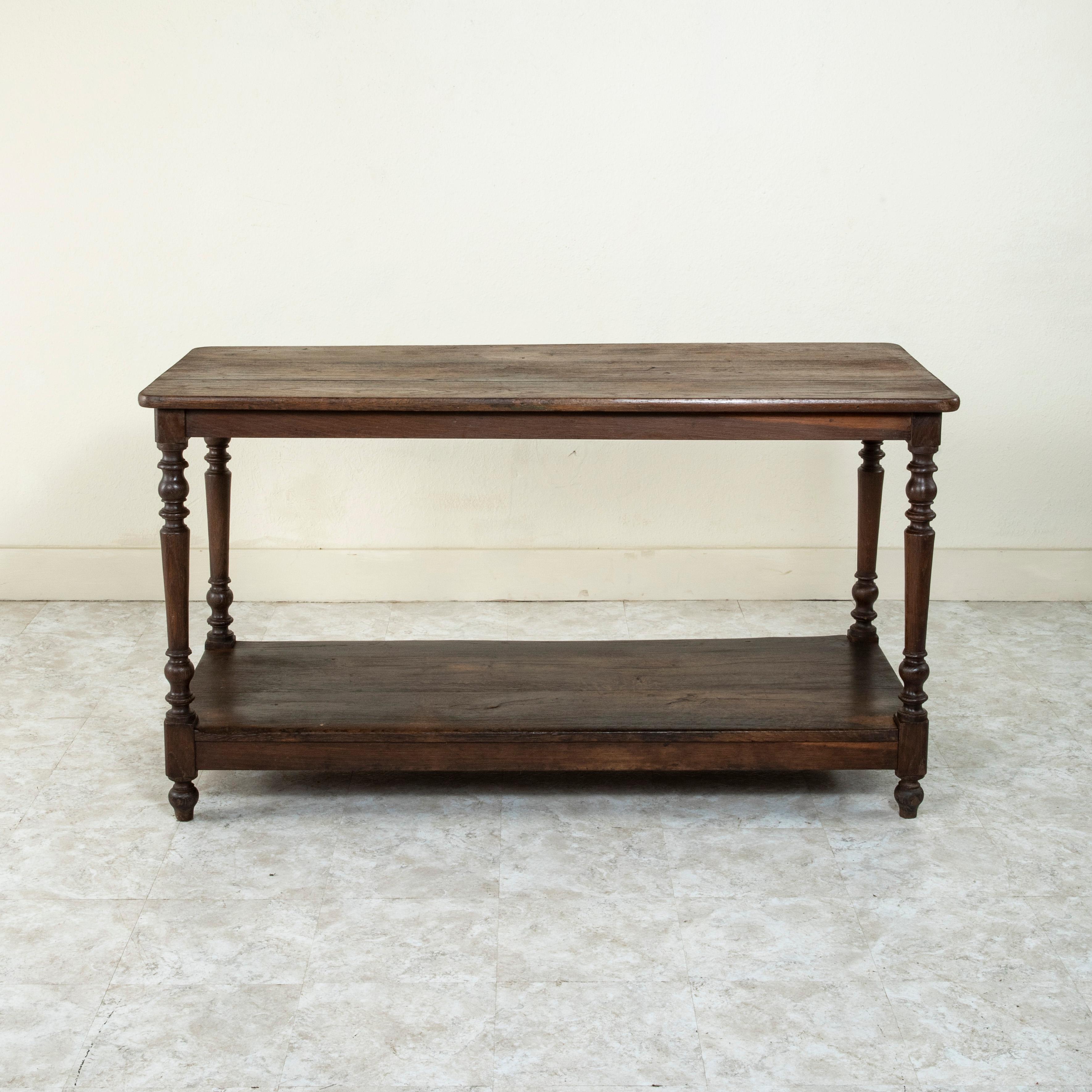Originally used in a French fabric store to lay out and cut fabric at the turn of the twentieth century, this oak silk trader's table rests on tapered turned legs which support its lower shelf. This draper's table, with its lower shelf for storage