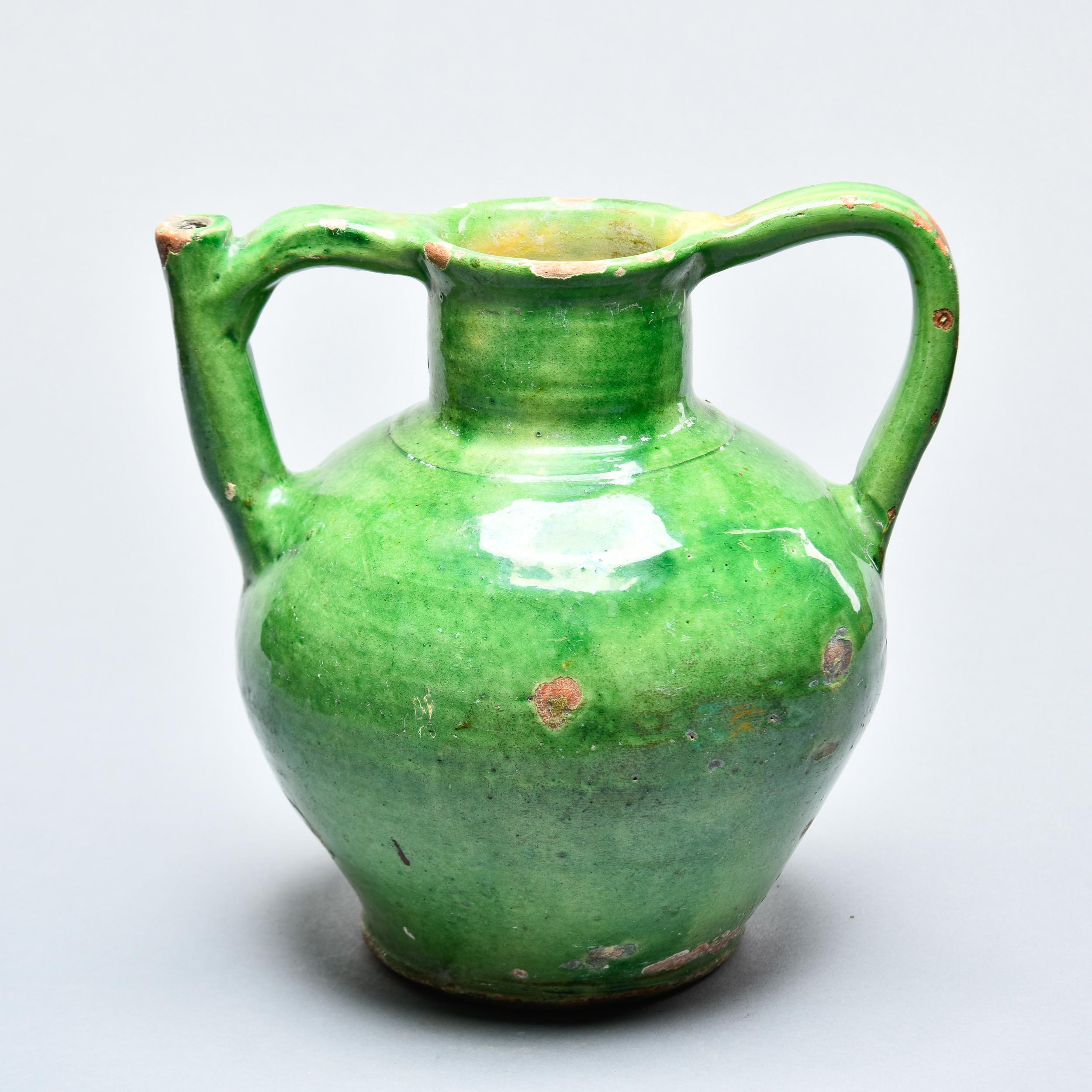 Found in France, this green glazed ceramic water jug dates from approximately 1910. Classic provincial amphora shape with one of the handles incorporating a functional pouring/filling spout. This most likely had a wooden lid at one point. Makes a
