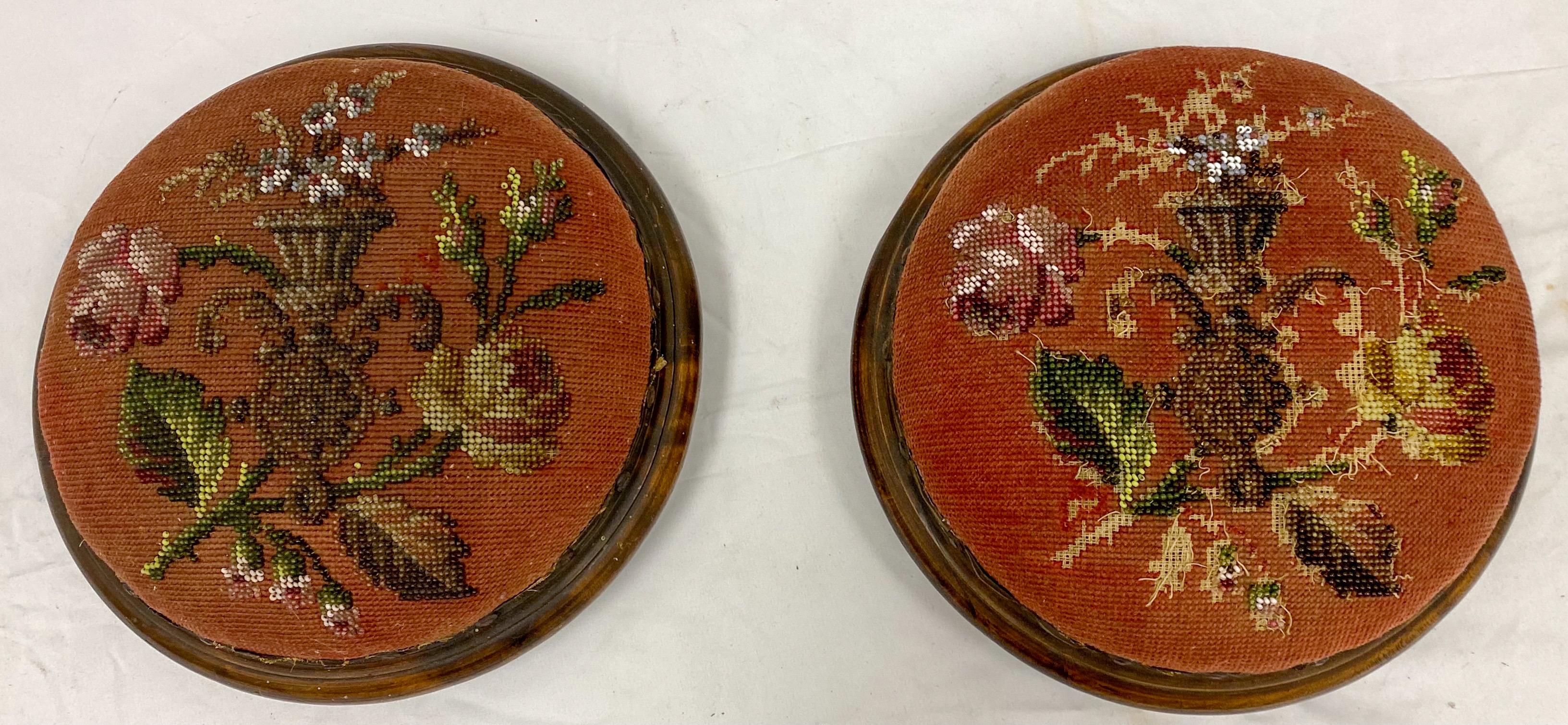 This is a lovely pair of early 20th century French Victorian style burl walnut and beaded ottomans. The subject matter is a neo-classical urn with sprays of floral foliate. They do show some age appropriate wear.