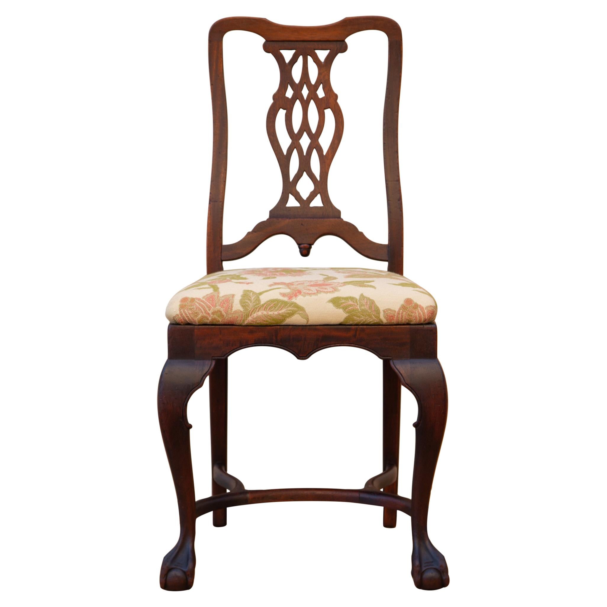 George II-style carved walnut side chair with trapezoid drop in seat, cabriole legs, curved H stretcher and claw and ball feet by Brower Furniture, Grand Rapids MI, circa 1920s. The seat is upholstered in new fabric with coral and green florals