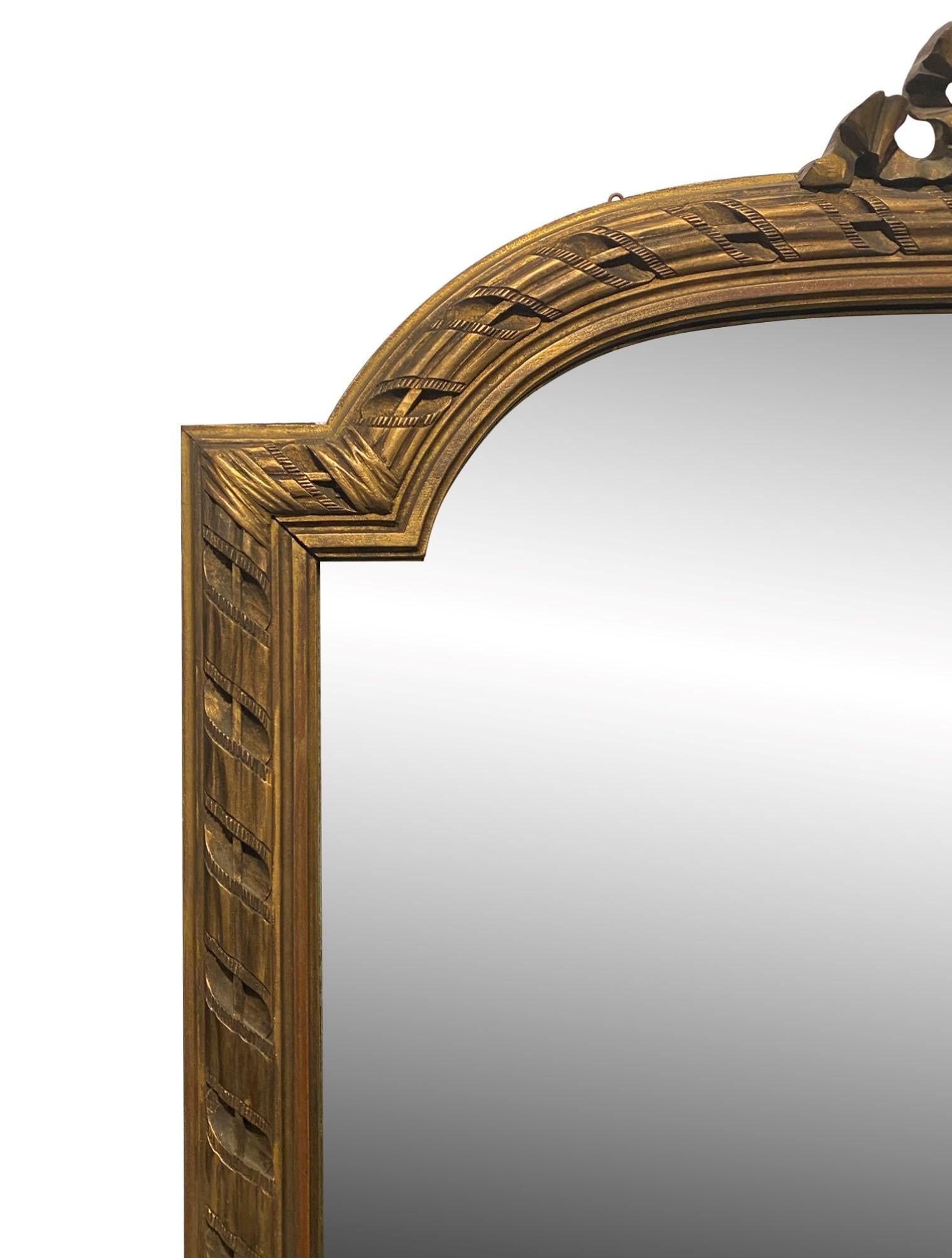 Early 20th century hand carved wood French gilded over mantel mirror done in the Louis XVI style with decorative details surrounding the frame and a ribbon motif in the top center. This can be seen at our 333 West 52nd St location in the Theater