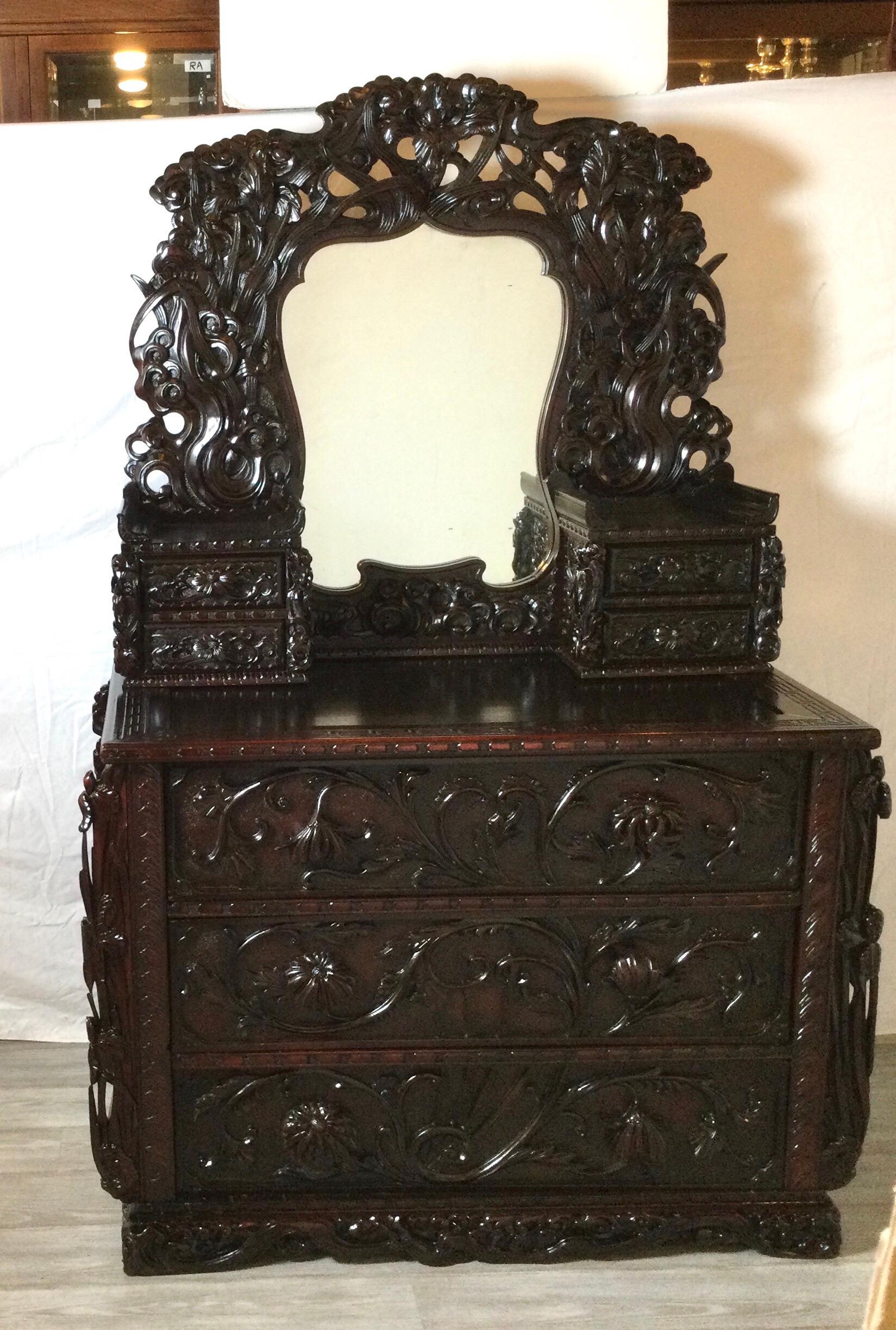 An elaborately carved Japanese chest of drawers with mirror. The chest with three large drawers with carved fronts with a mirror with intricately carved frame with two smaller drawers on each side, flanking the mirror. 

Measures: 46
