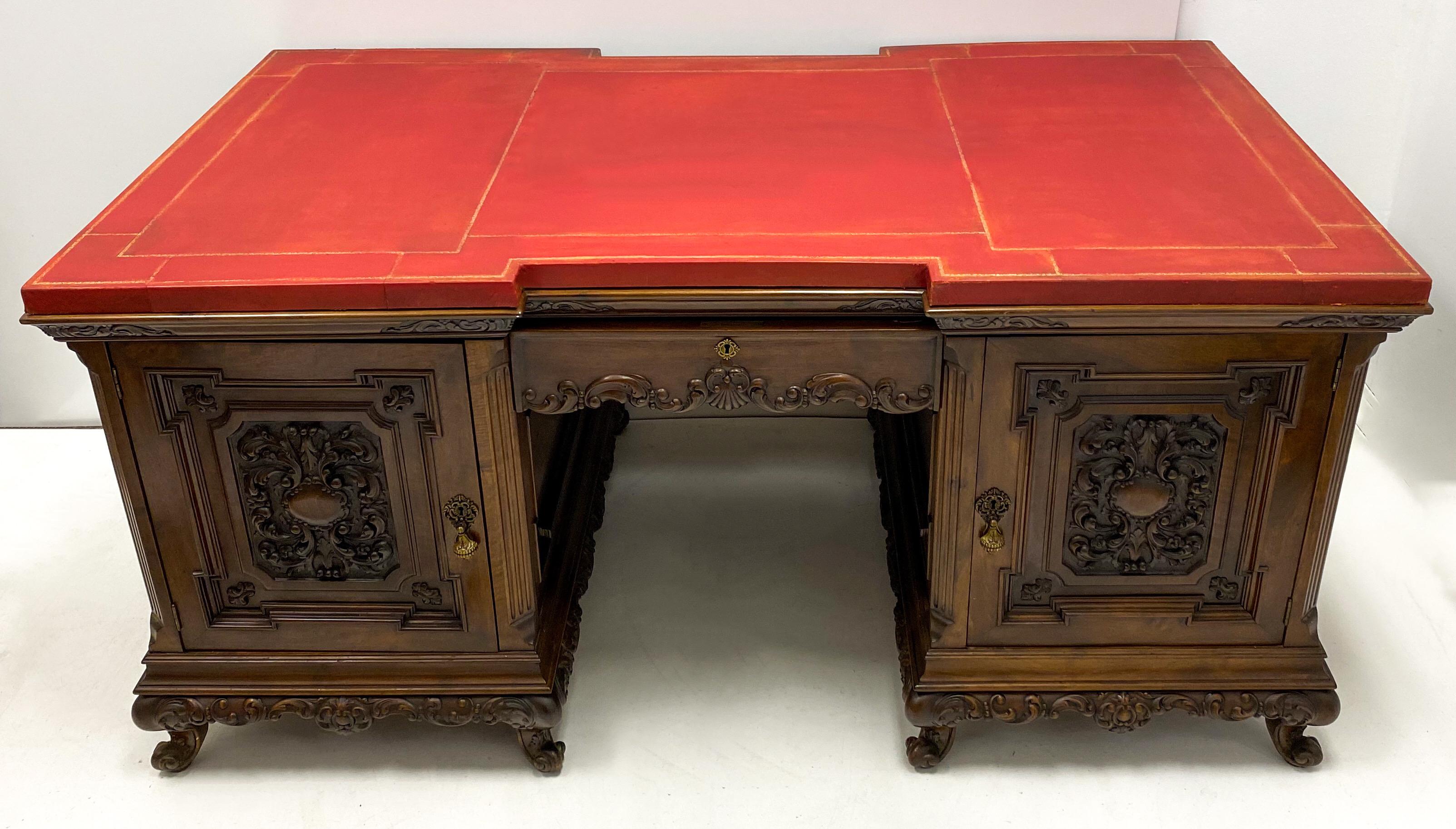 This is a wonderful 1930s Italian carved walnut desk with an embossed red leather top. It breaks down into pieces for ease with regard to shipping. It is carved identically on both sides, but only one is fully functional. The piece has hand carved