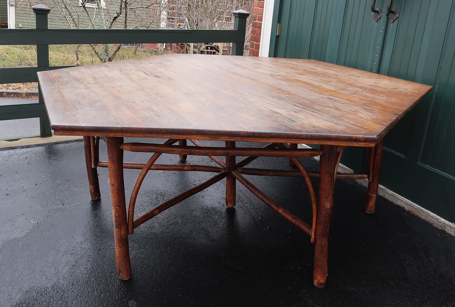 Early 20th C Old Hickory hexagonal shaped dining table. Made by Rustic Hickory Furniture Company, La Porte, Indiana. Circa 1915.

It has a hexagonal oak top and an elaborate hickory pole base with arches and crossed stretchers. It comfortably