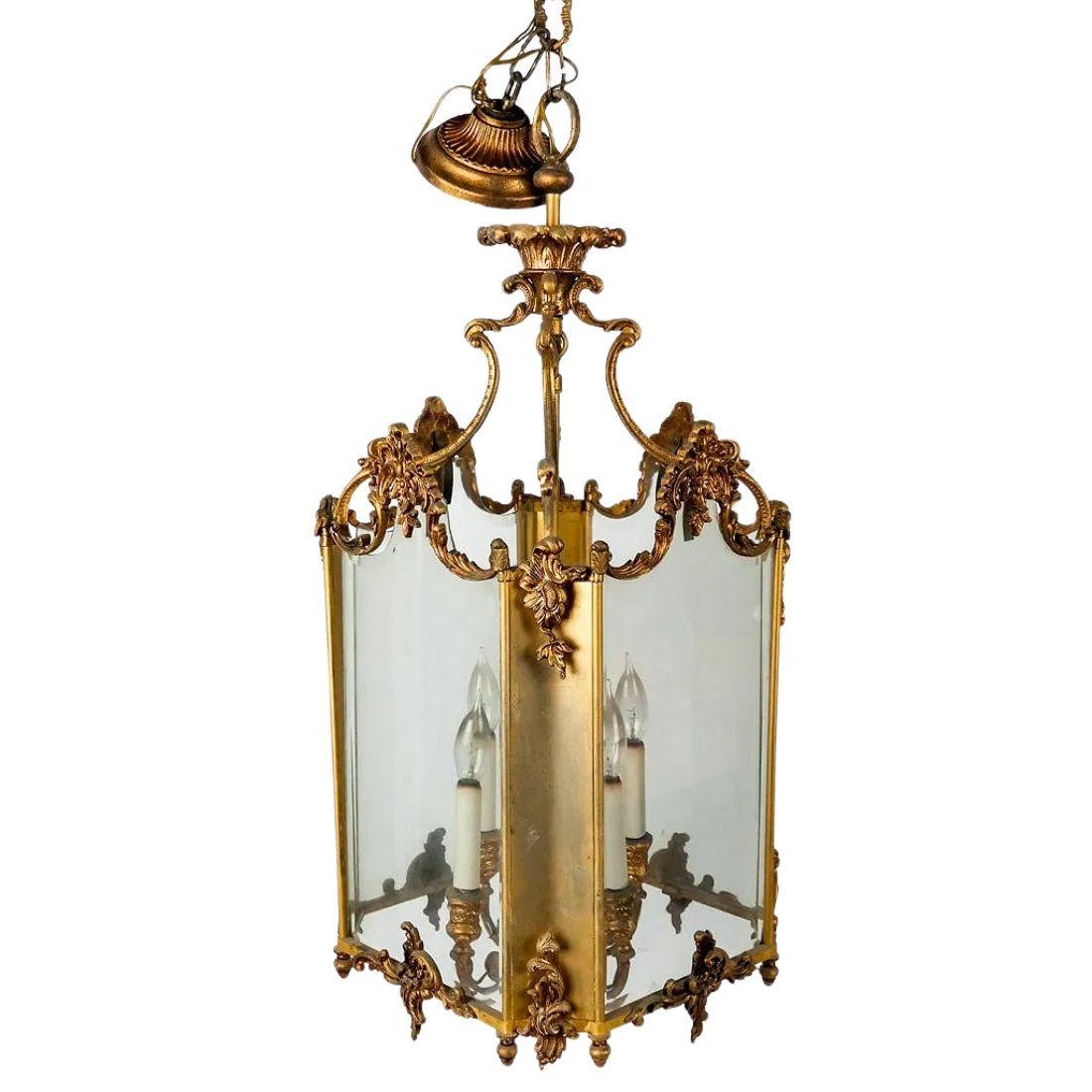 This elegant early 20th-century lantern is designed in the Louis XV style, showcasing the graceful curves and ornate detailing characteristic of the period. The gilt metal frame is richly adorned with finely cast acanthus leaf motifs and scrolling