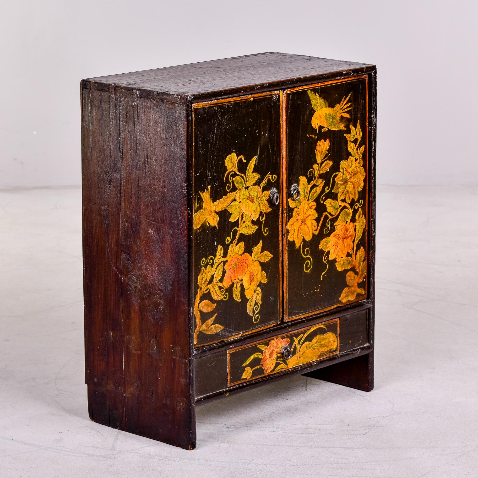 Circa 1910 small wood Chinese cabinet with two front hinged doors, single drawer at the bottom and one internal shelf. Hand painted with birds and flowers. Dovetail and mortis and tenon construction.