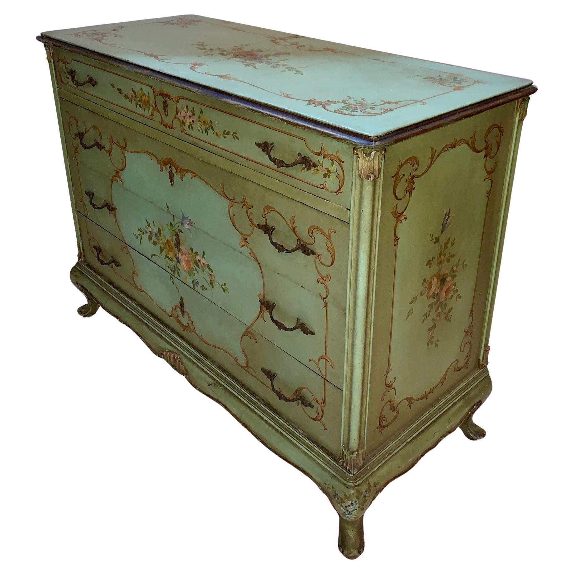 An elegant and beautiful Louis XV style Venetian floral paint decorated and partial gilt four drawer dresser consisting of a full length narrow accessories drawer above three large drawers. This piece is done in beautiful calming green tones and a