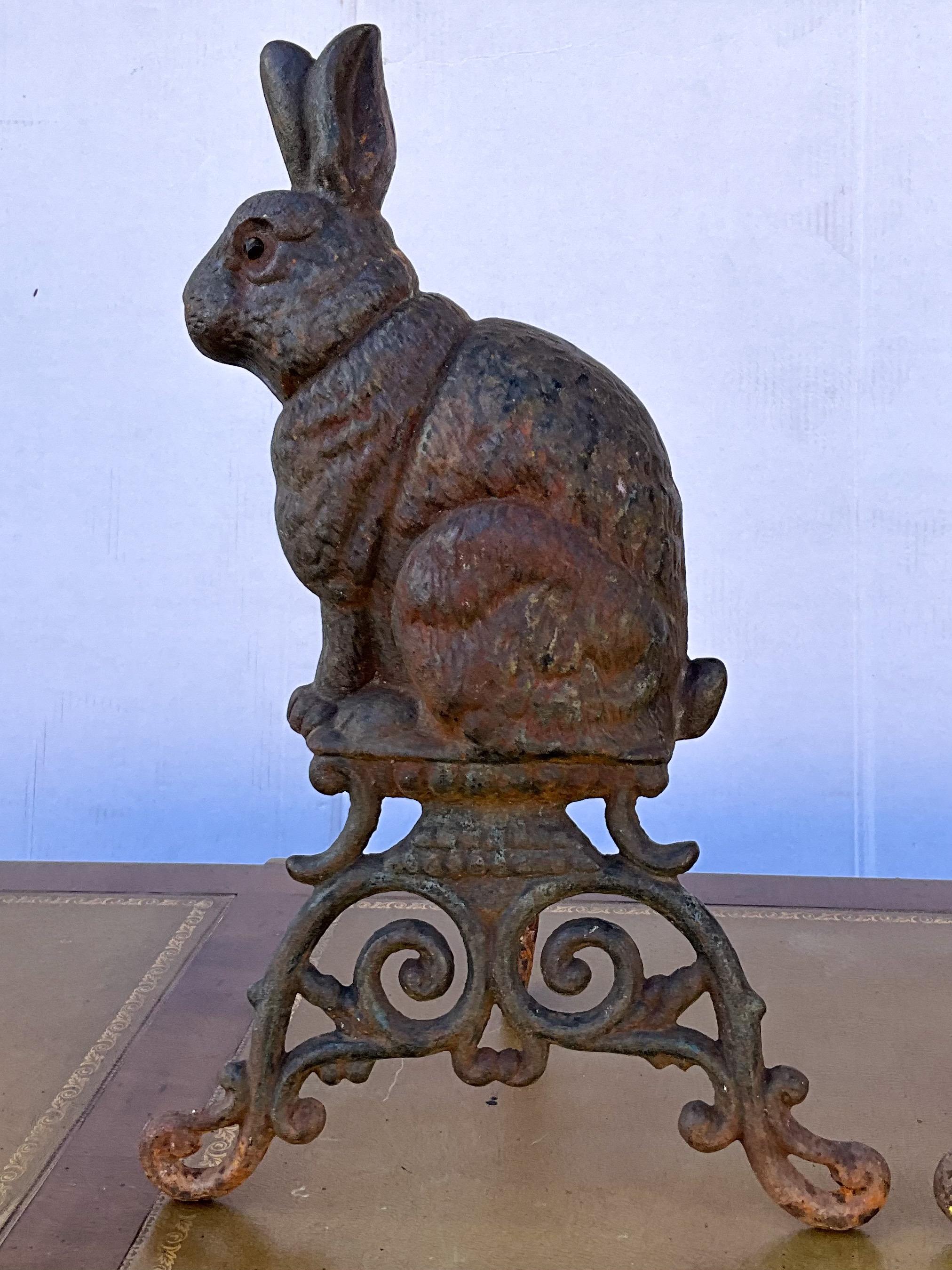 This is an early 20th century pair of Victorian style rabbit form andirons. They show some general age wear. They are unmarked. The support iron folds closed.