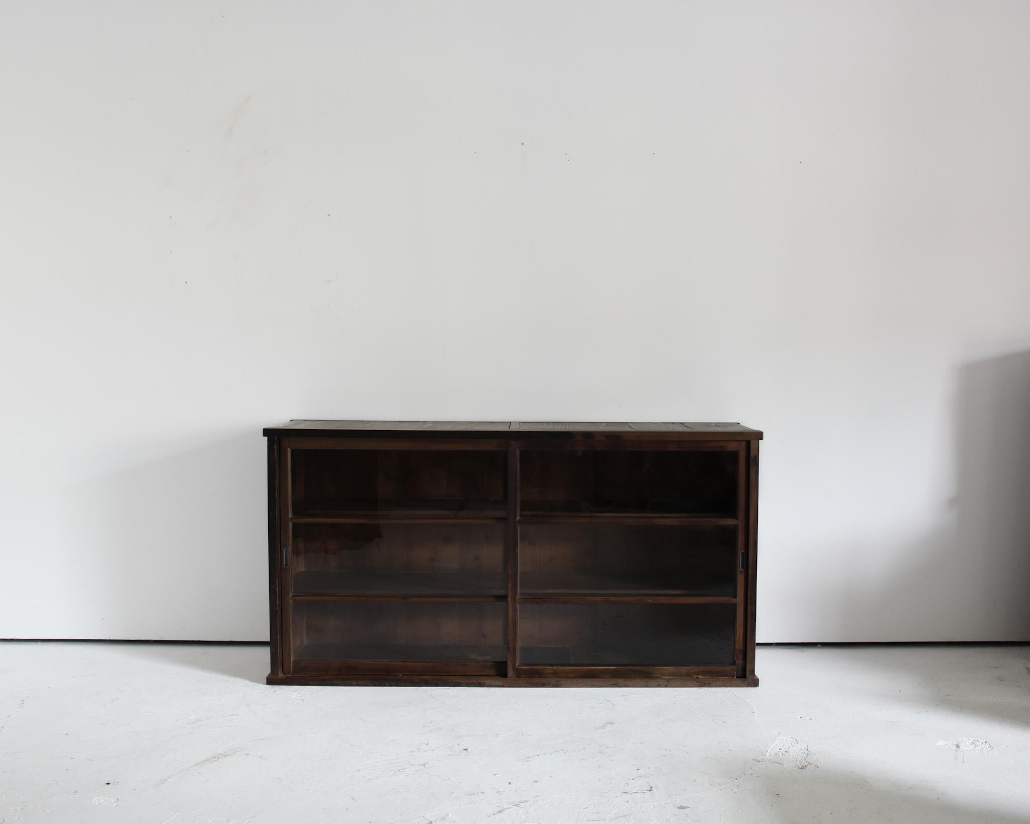 A late Meiji period Japanese tansu sideboard.

Constructed in cedar with original wavy glass sliding doors (one pane has been replaced).

Heavily patinated with two interior shelves.