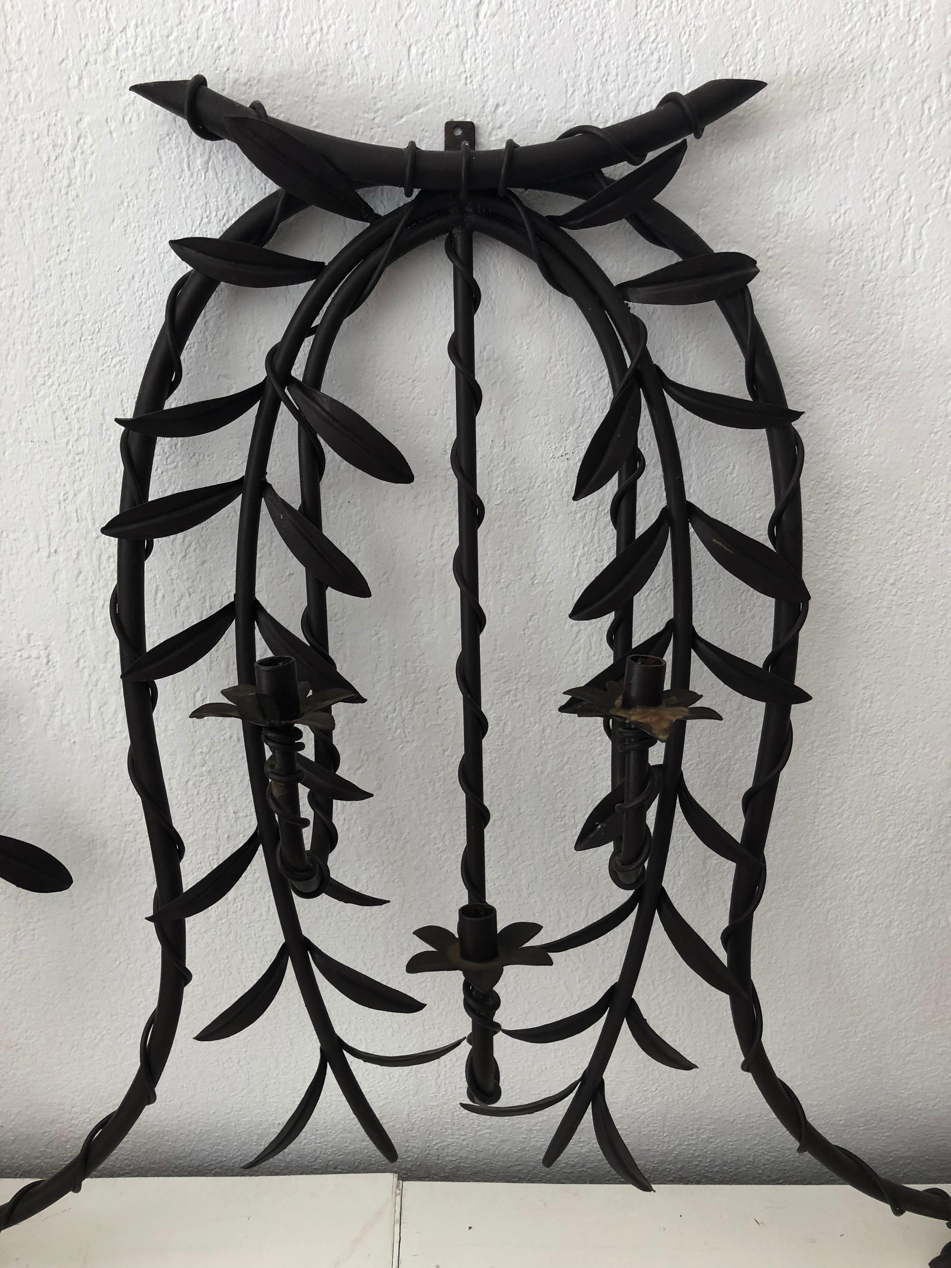 A majestic early 20th century wrought iron wall scone finely hand carved and featuring hanging leaves. The sconce holds 7 candles. It is currently not electrified/wired, can be done upon request

Dimensions: 70