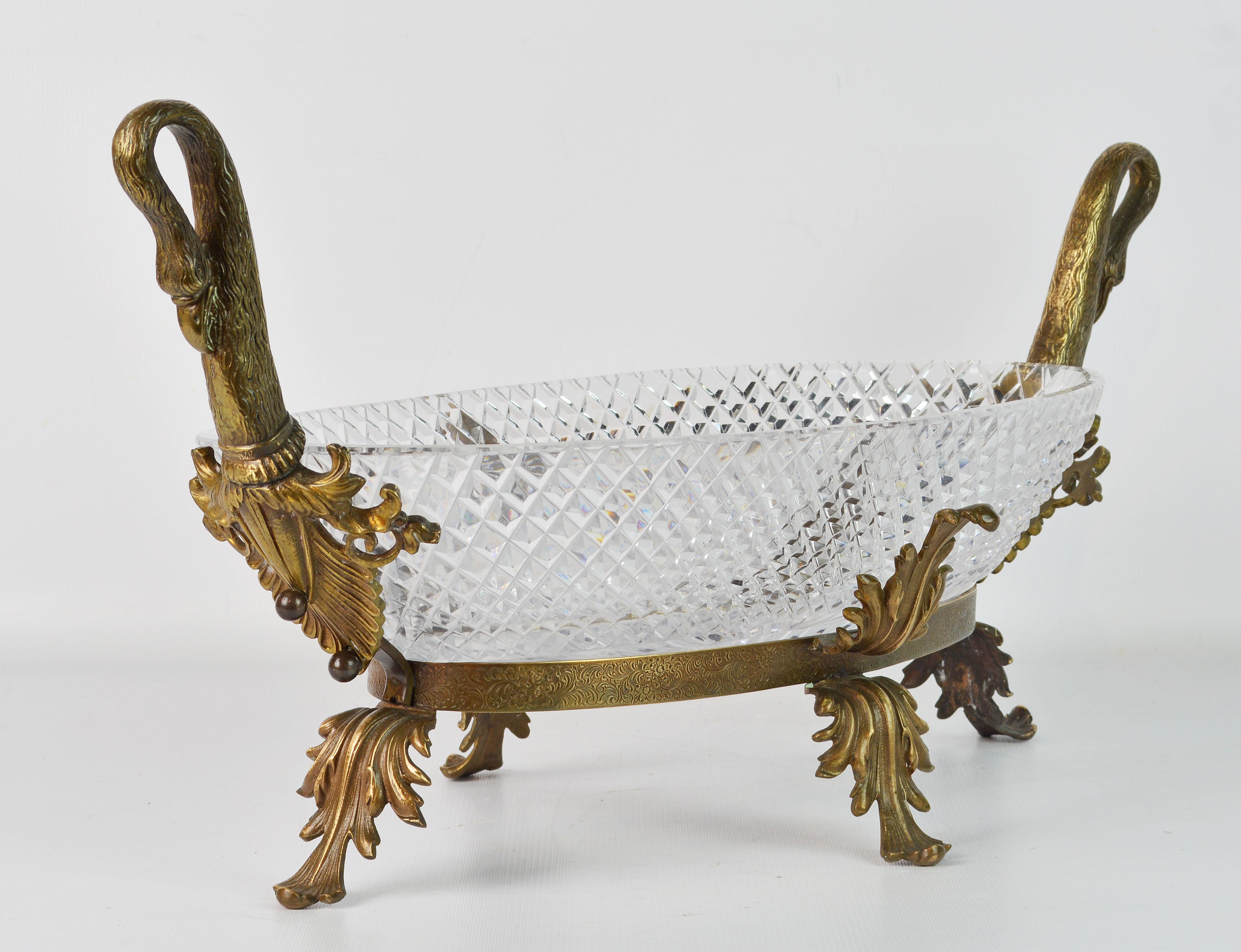 This is a rather unique center piece with a stand of leaf-work gilt bronze crested by two elegantly curved handles in the shape of flamingo necks and heads in the Empire tradition. Every detail is well crafted and the oval diamond cut crystal bowl