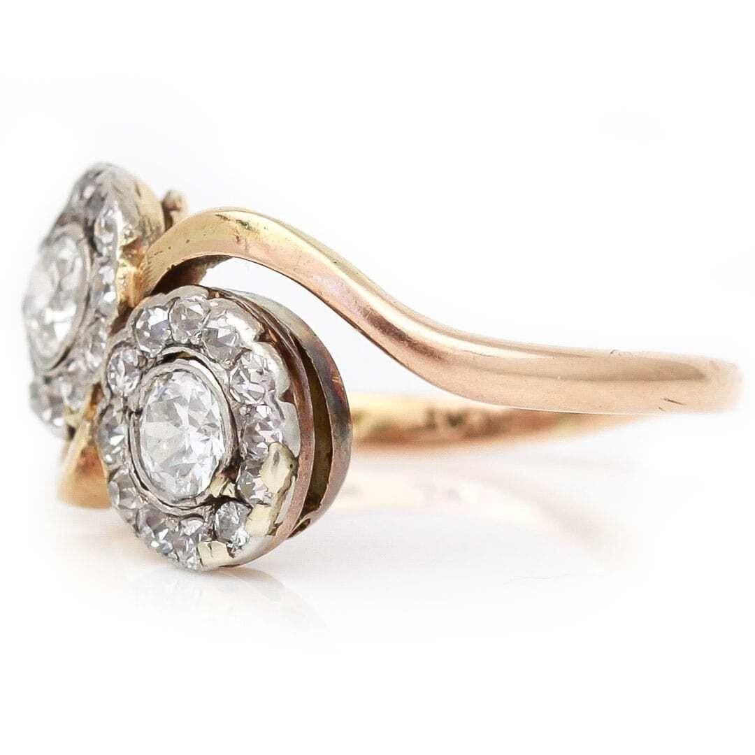 A unique antique 18ct yellow gold and platinum two stone cross over diamond cluster ring often referred to by its French name ‘toi et moi’ translated to ‘you and me’. Set with two, bright old cut diamonds approx. 0.25ct each and bordered by twelve