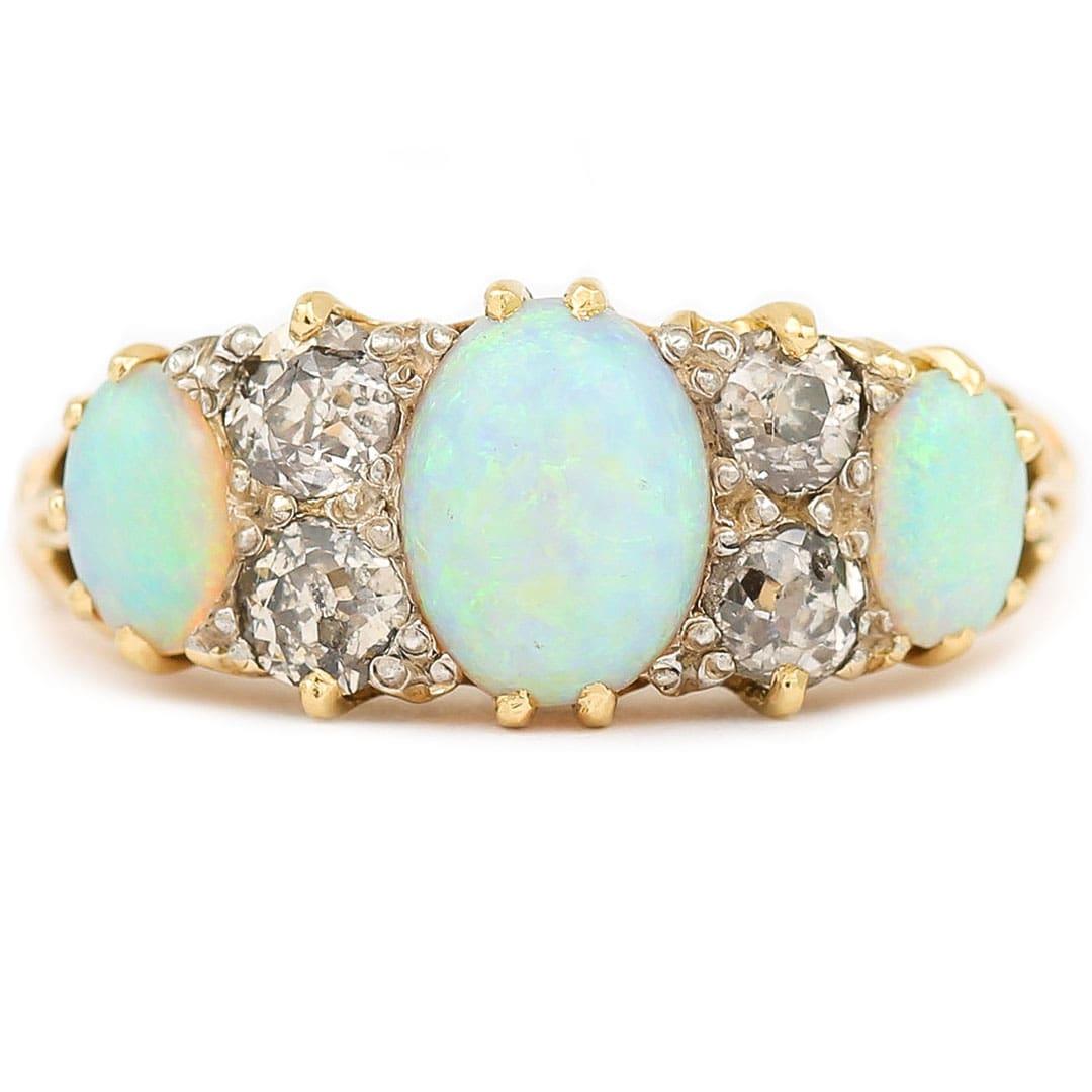 An impressive early 20th century 18ct yellow gold, opal and diamond three stone gypsy style ring. All the gemstones are claw set with the opals displaying a great play of colour showing predominantly turquoise hues with flashes of electric blue and