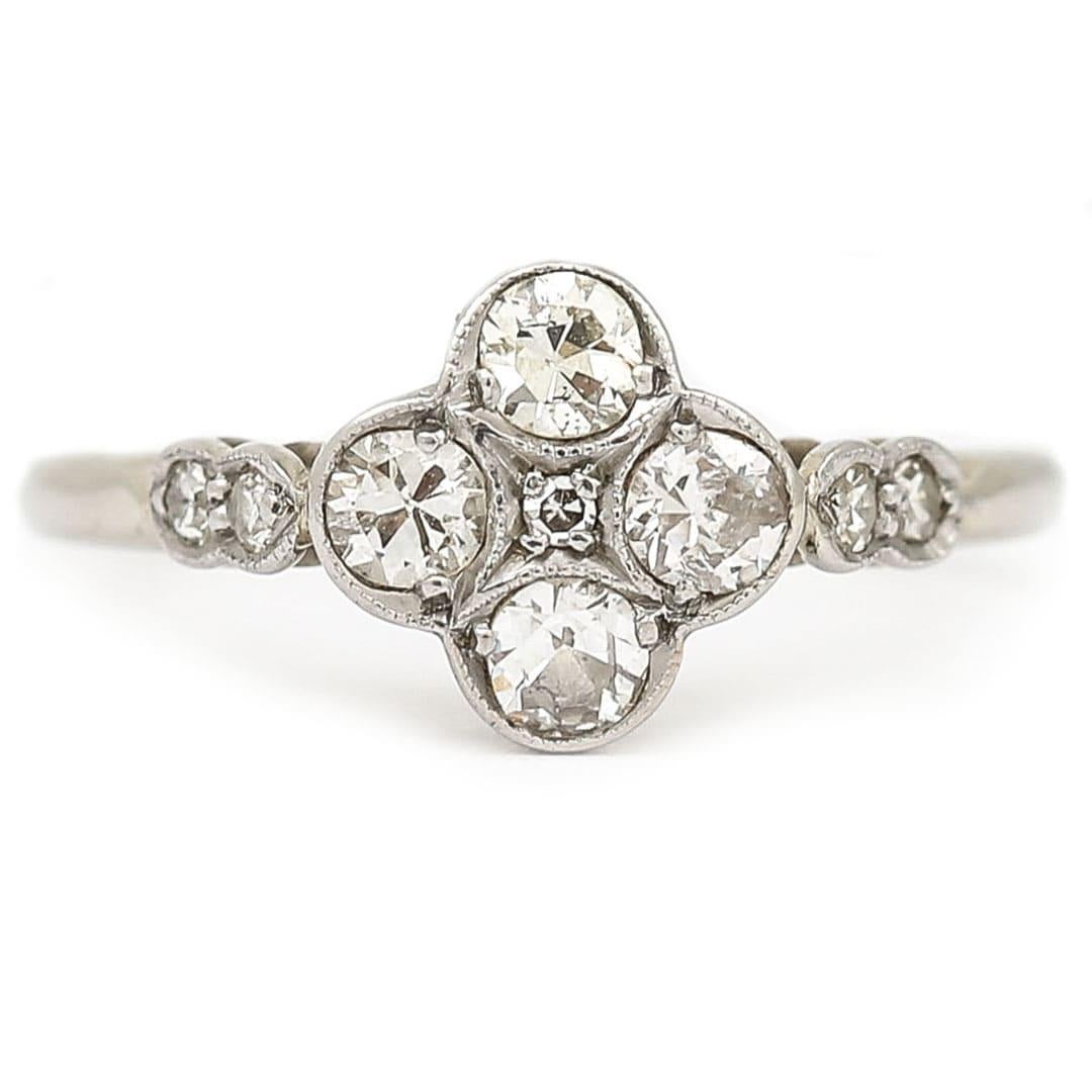 A delightful 18ct white gold and platinum four stone diamond ring with an estimated total 0.45ctw. An unusual quatrefoil design using bright old cut diamonds in a flower design with a small centre diamond. With diamond set shoulders too, the setting