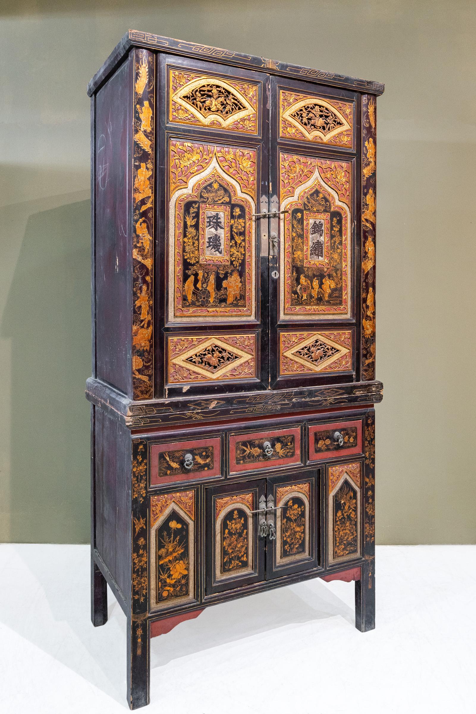 An early 20th century 2-tier carved cabinet from Fujian province, specifically Quanzhou city, China. 
This is a very unusual cabinet as it is much more decorated than usual. 
On the top section, on both sides of the cabinet frame are paintings of
