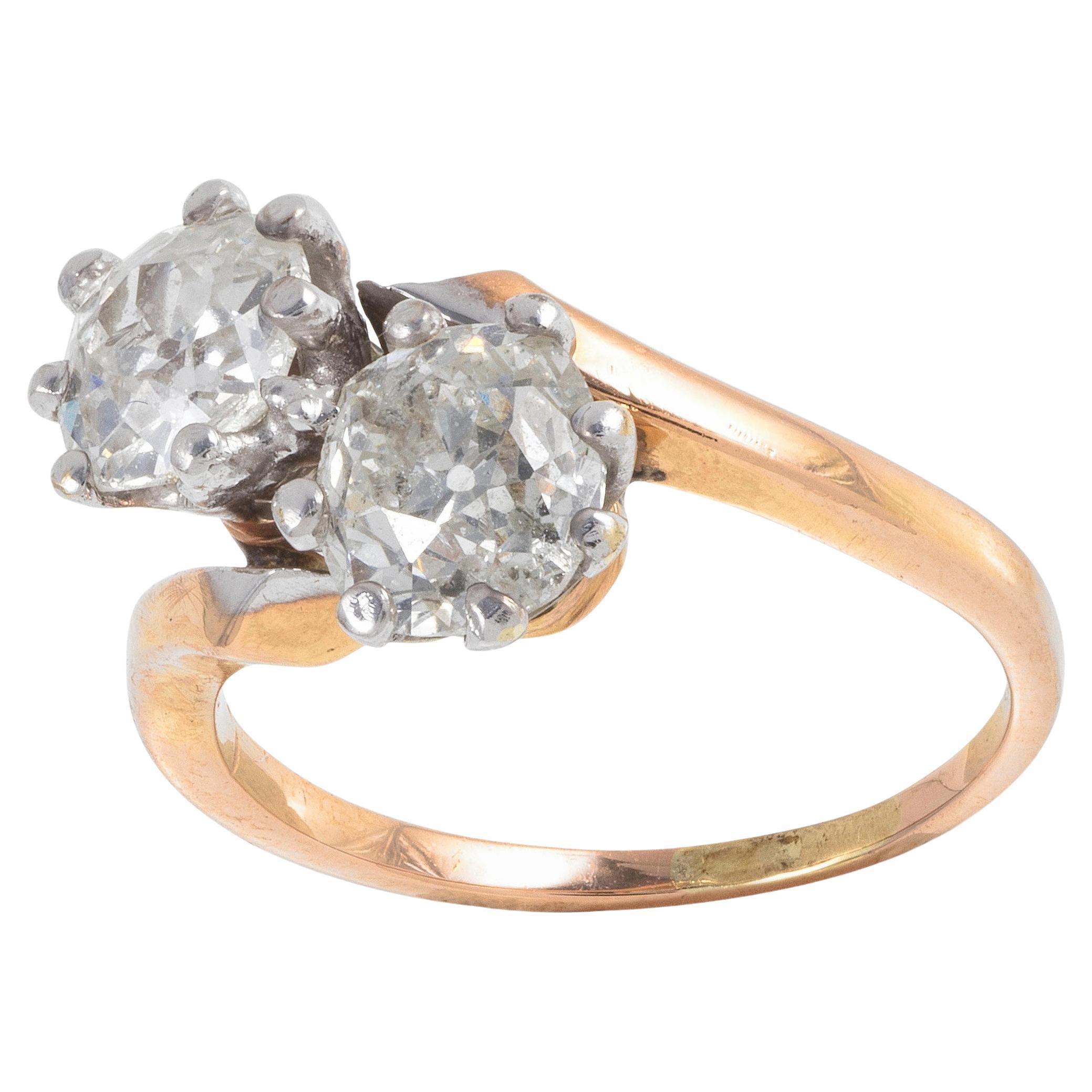 Anillo cruzado de diamantes de principios del siglo XX que sostiene dos diamantes talla antigua con un peso aproximado de 2,4 ct, en un engaste de diamantes talla antigua. Engastado en oro amarillo de 18 quilates y platino. 
Talla 6 1/4. 
Peso bruto