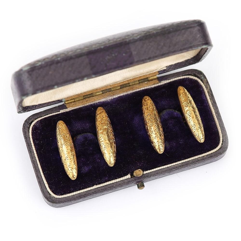 A pair of antique 9 Karat gold torpedo shape cufflinks with engraved top and chain link to either side of the torpedo sections. The engraving has been produced as a scroll pattern and is hand engraved which remains clear with little signs of wear.