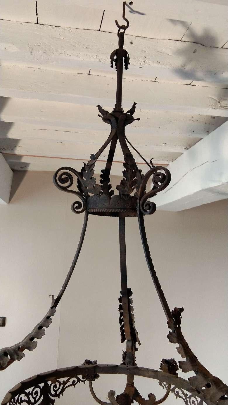 This antique, rustic iron chandelier was created in France, circa 1900. Louis XV style chandelier with 9 arms decorated with metal acanthus leaves and shells around the circle, roses on the candle holders.