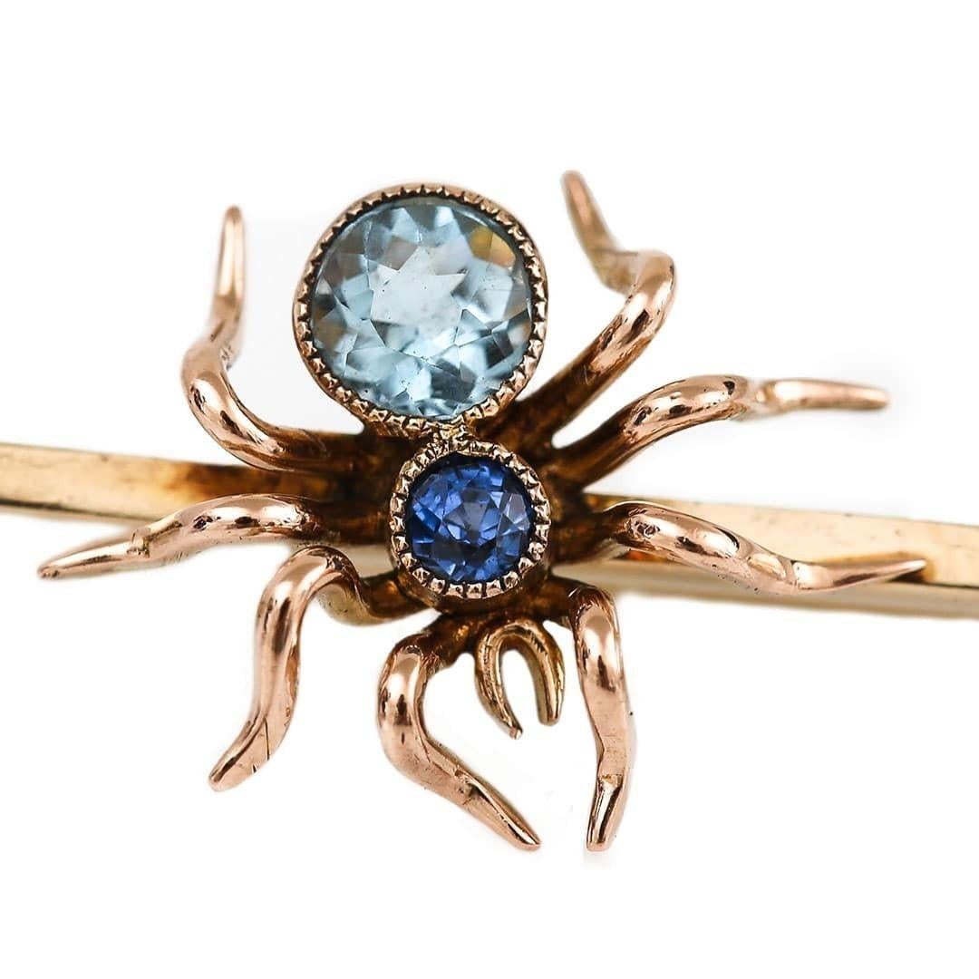 A beautifully crafted early 20th century 9ct yellow gold spider bar brooch set with a light blue topaz body and a deep blue sapphire adorning his crown. In fantastic condition and so contemporary in its appeal the brooch measures 50mm long and is a