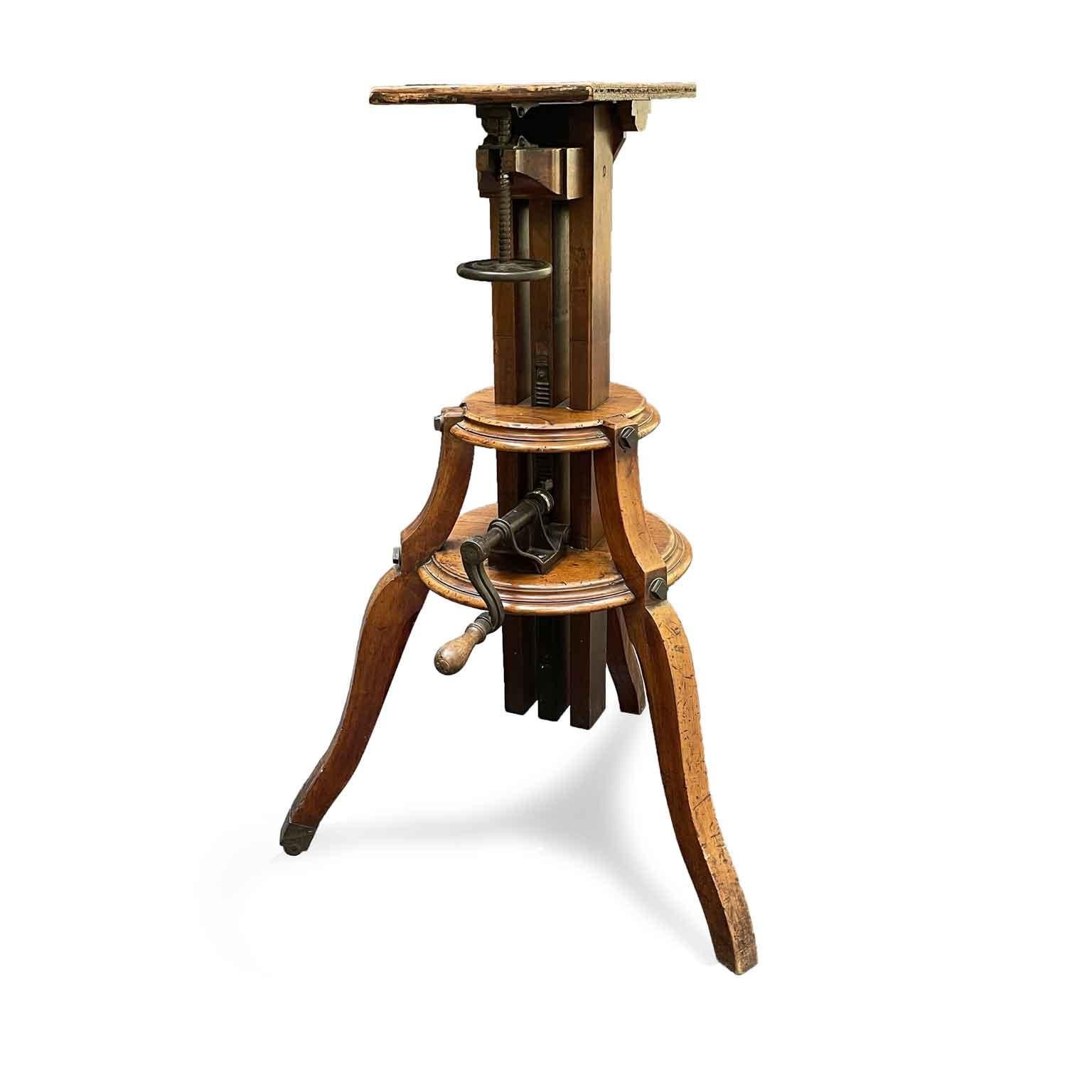 Early 20th century three-legged solid wood and iron camera stand, features a fully adjustable platform top that could be tilted up or be fixed as a flat surface and moved upward and downward by turning the oversized iron wheels which allows you to